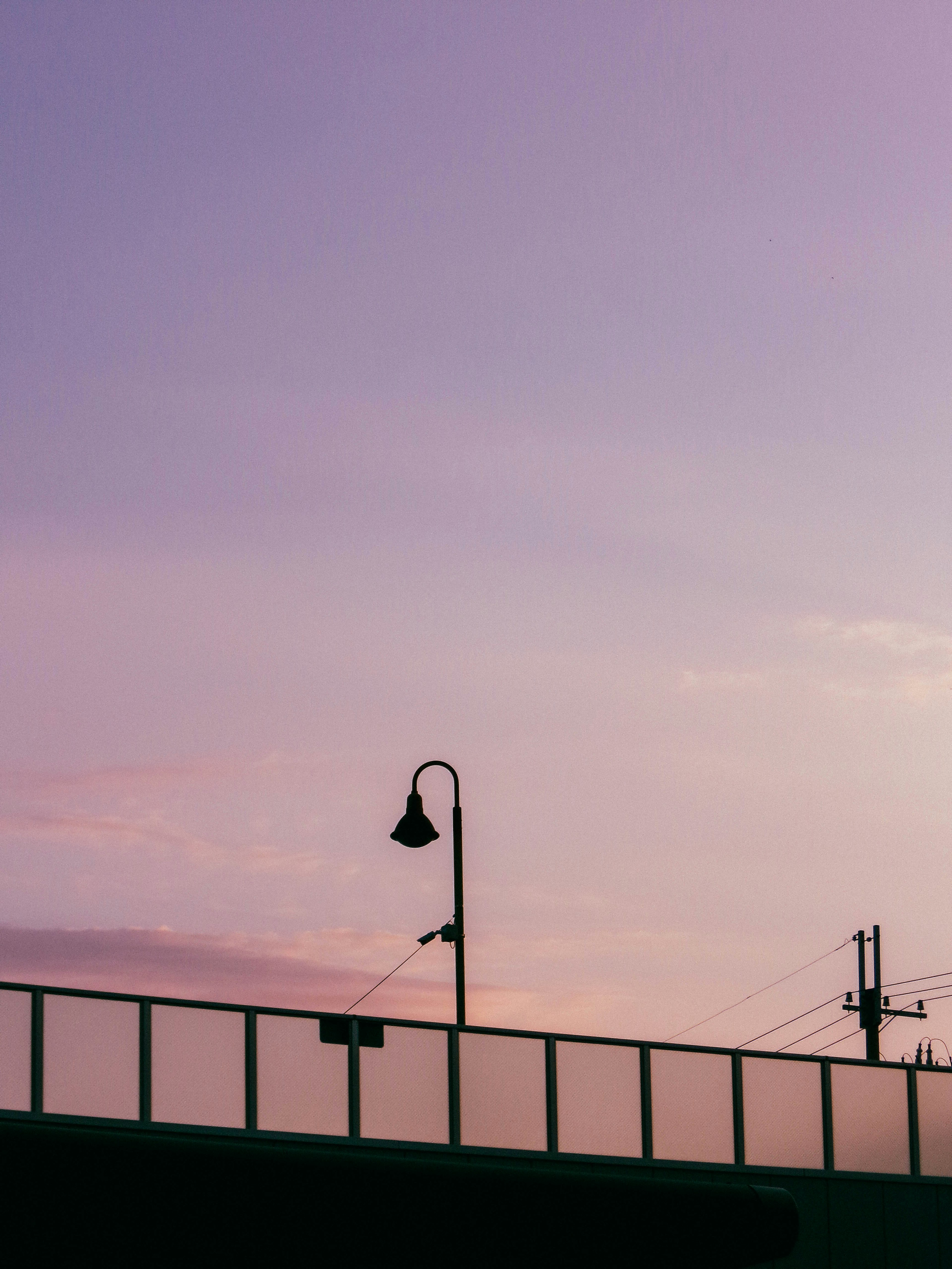 Silhouette d'un lampadaire contre un ciel de coucher de soleil pastel