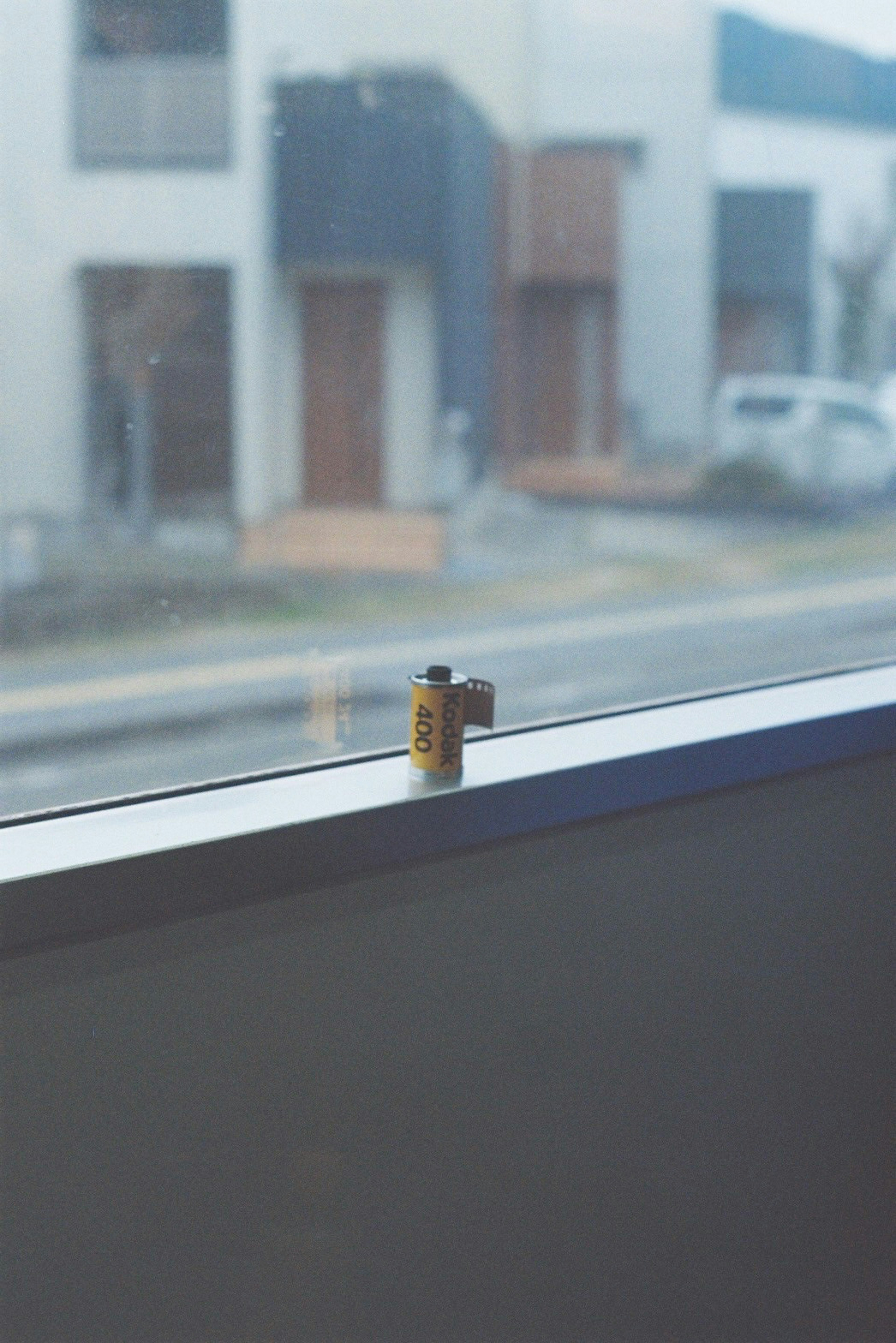 Cartucho de película colocado en un alféizar de ventana con edificios residenciales de fondo