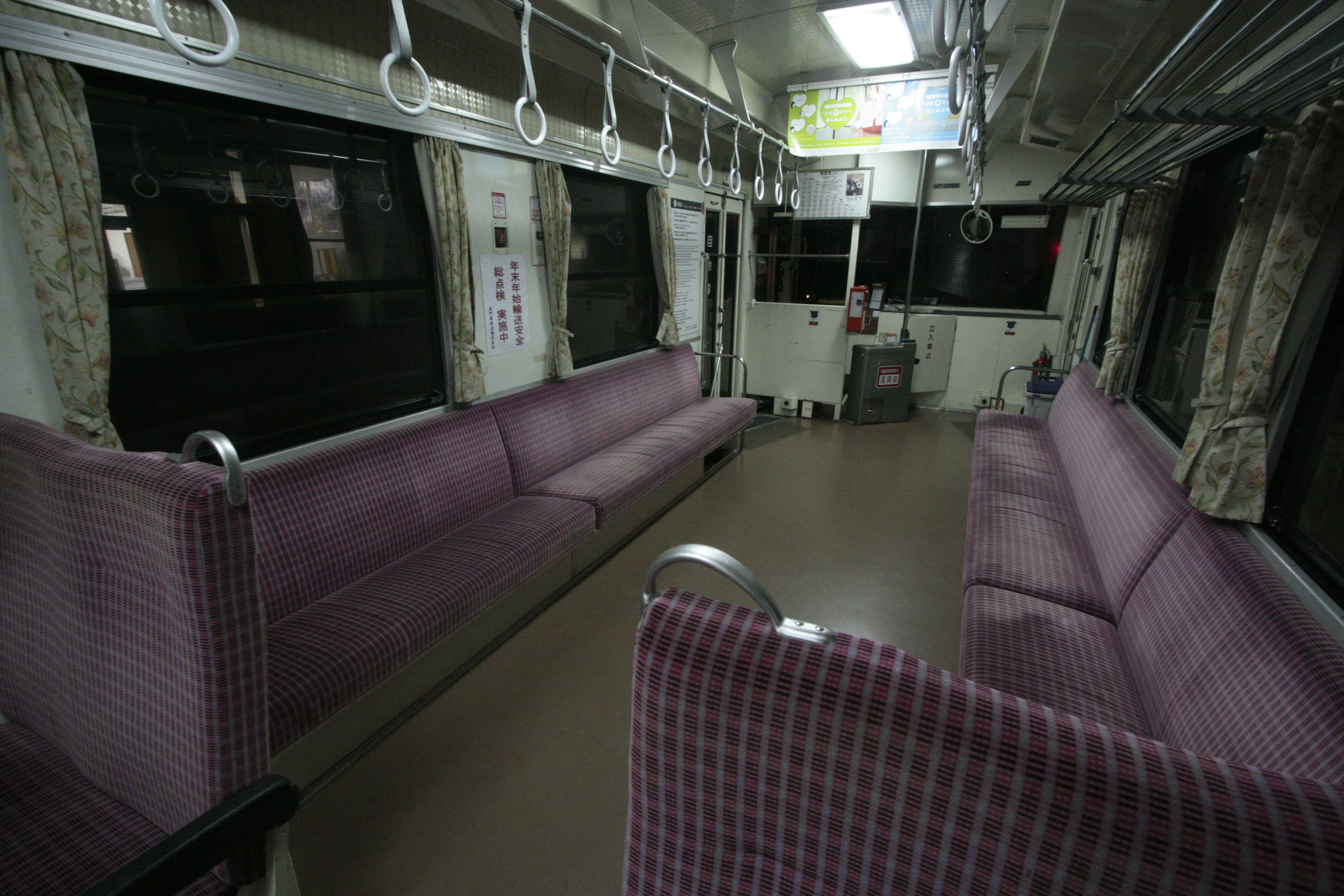 Interior of an empty train carriage with purple seats