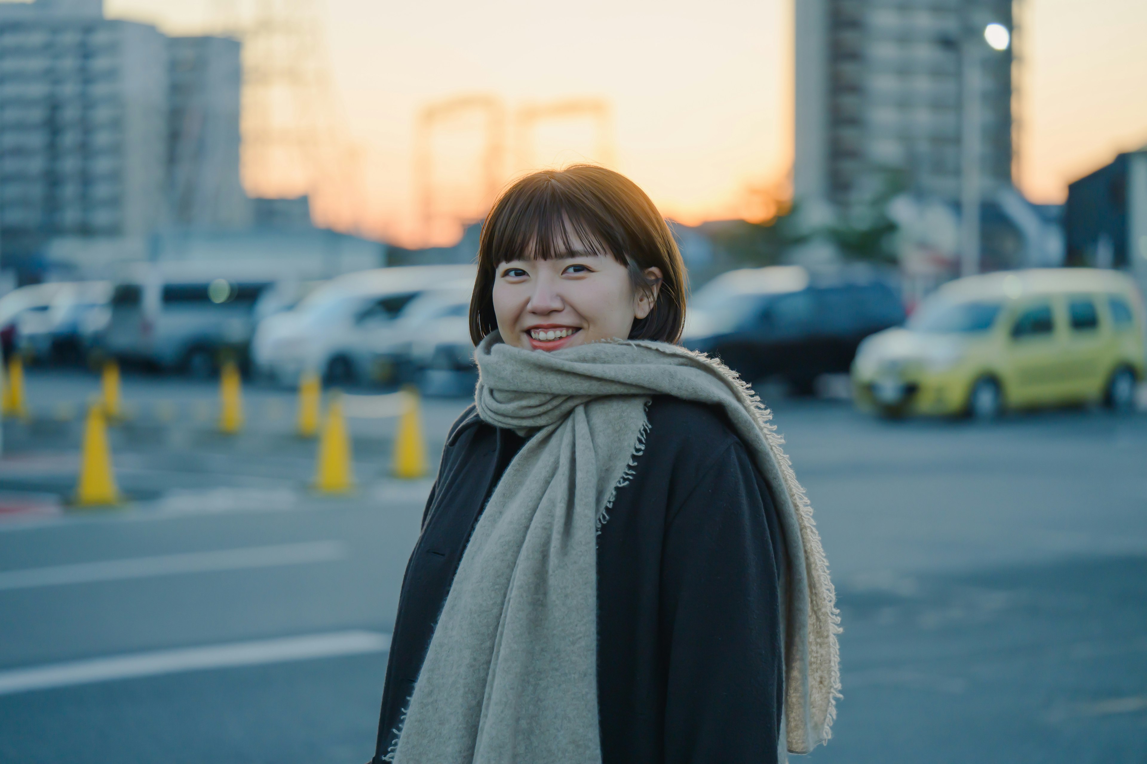 Femme souriante portant une écharpe au coucher du soleil