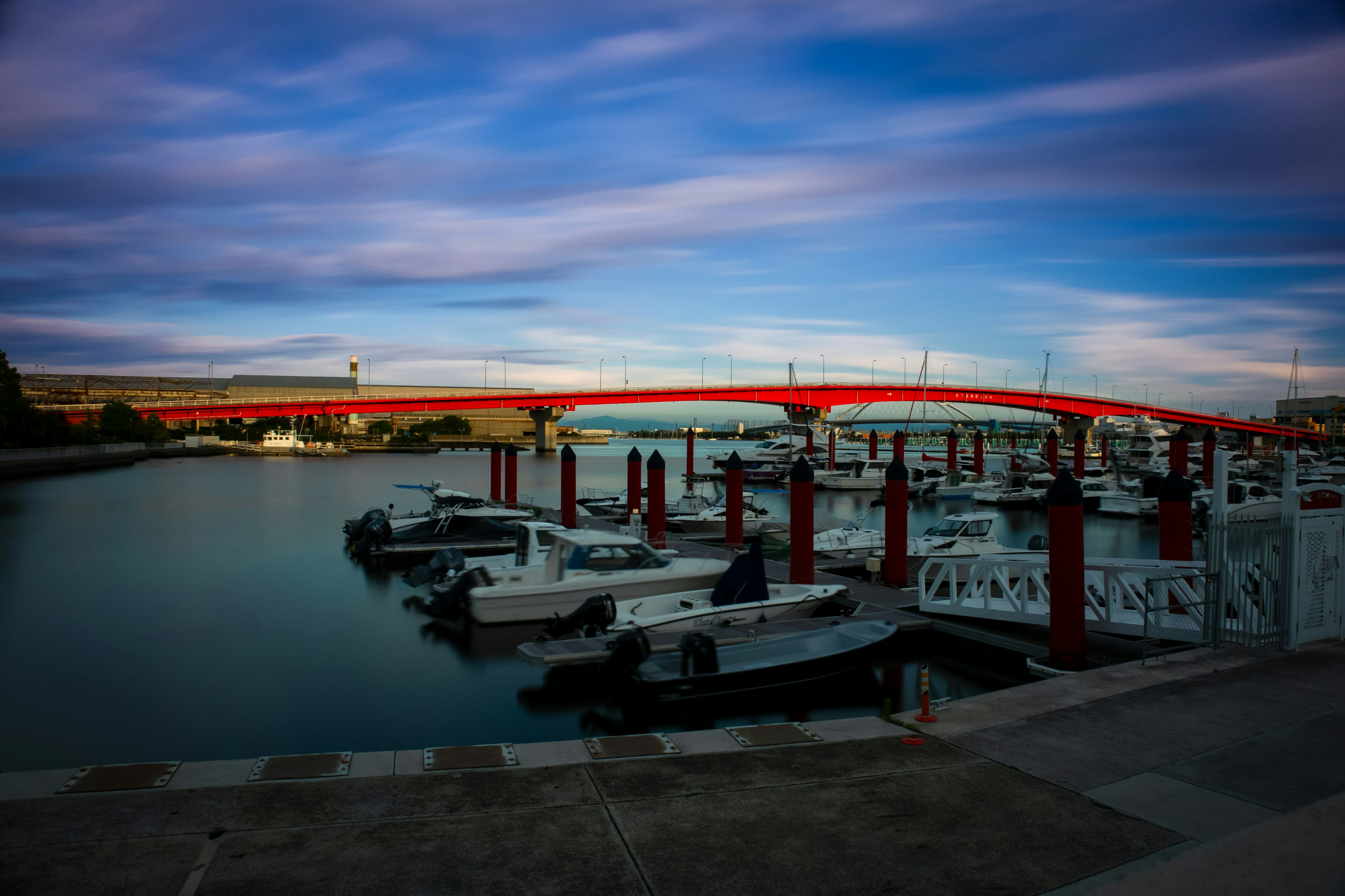 Vista escénica de un puerto con un puente rojo y barcos atracados