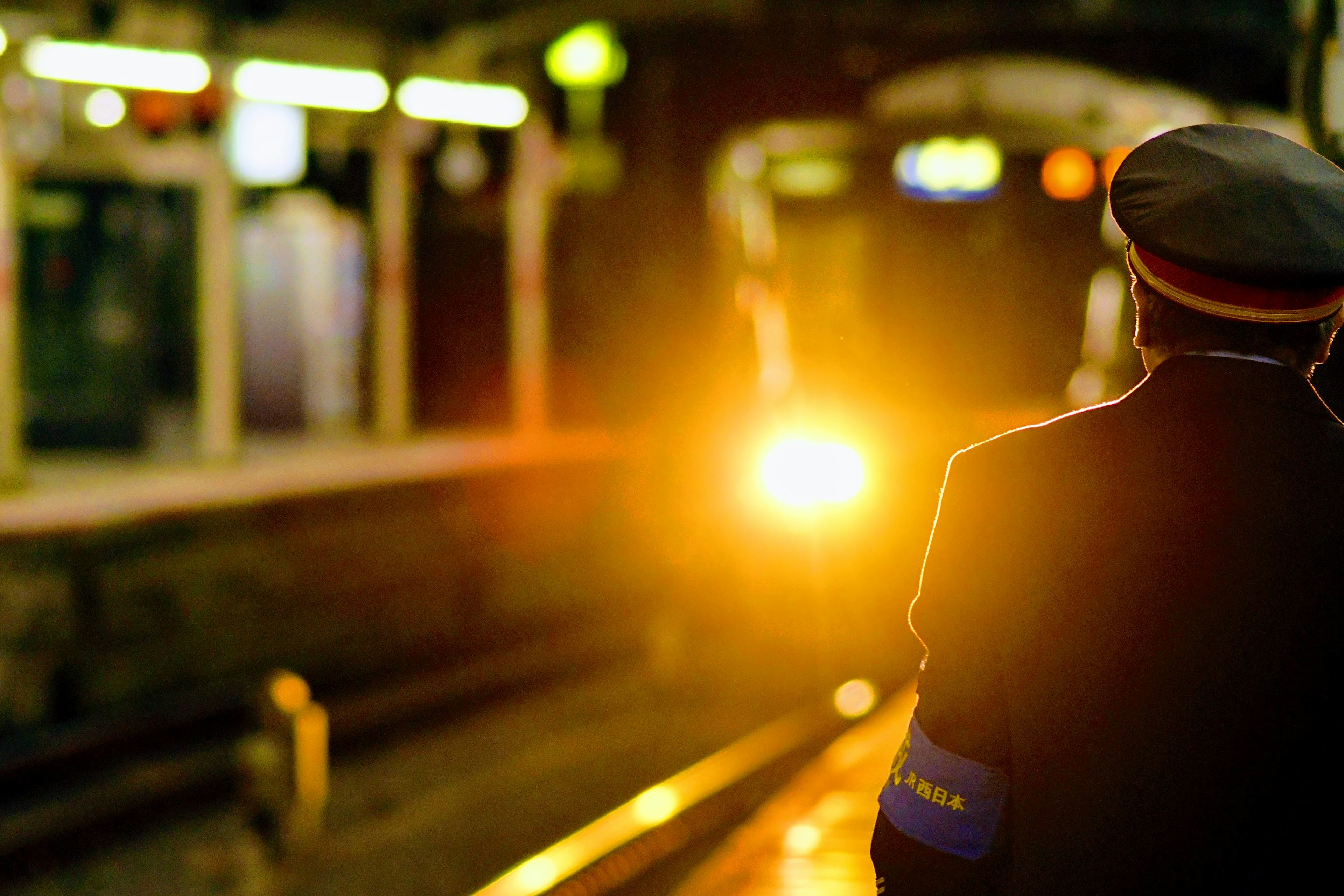 Gardien de gare attendant avec des phares de train illuminés en arrière-plan