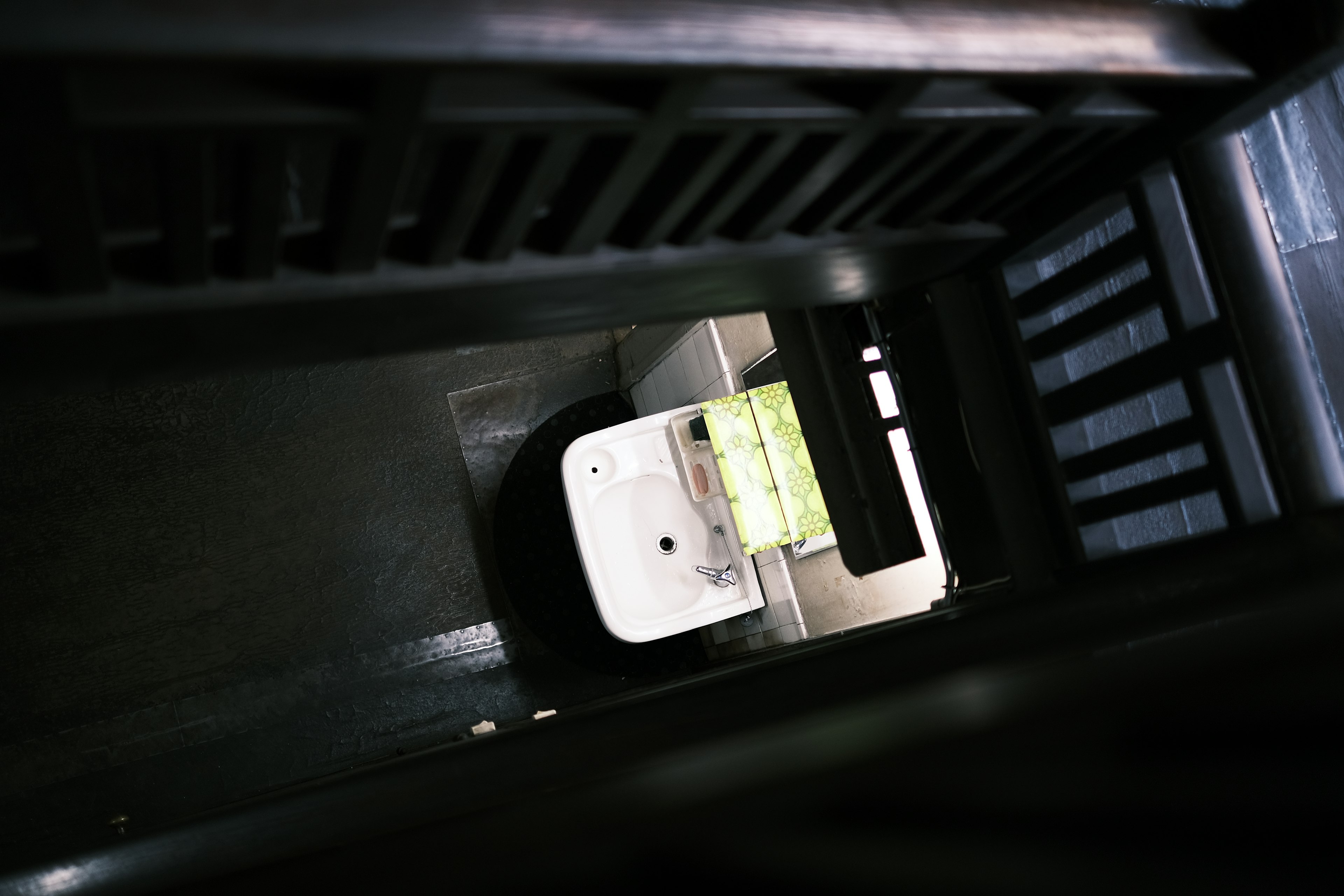 Narrow space viewed from above featuring a white toilet and green toilet paper