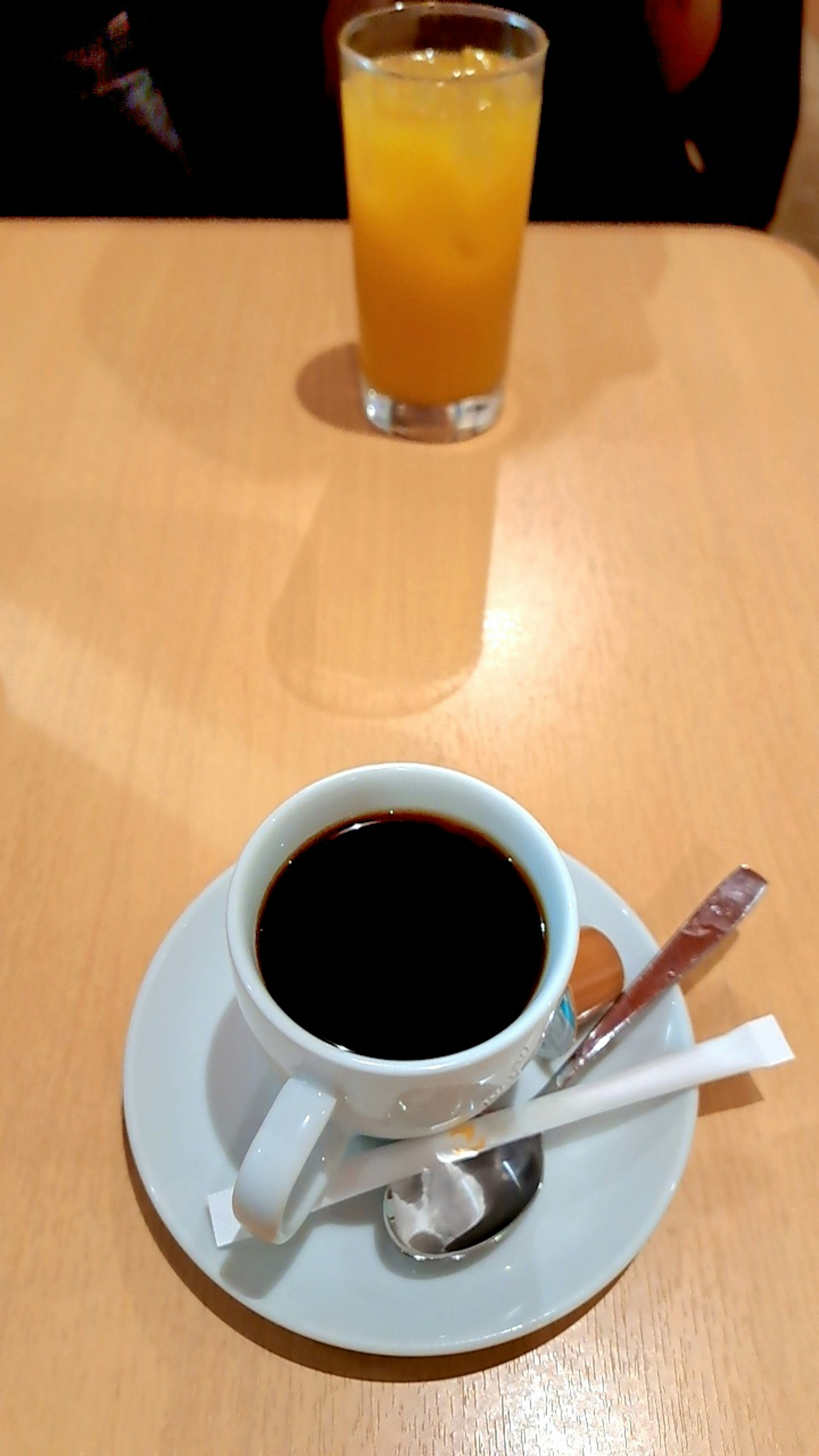 Taza de café negro y vaso de jugo de naranja sobre una mesa de madera