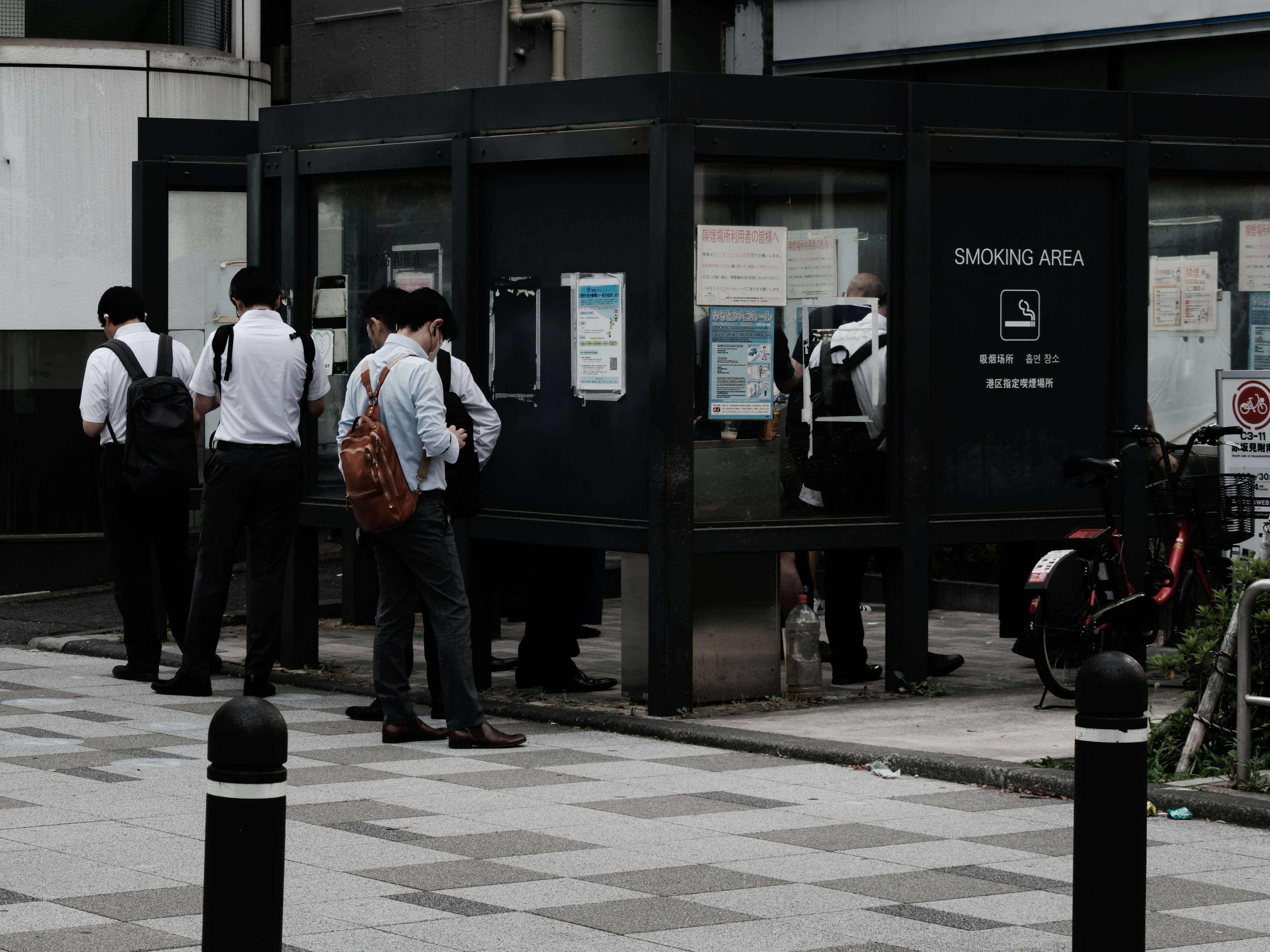 Escena urbana con personas de pie cerca de una cabina telefónica