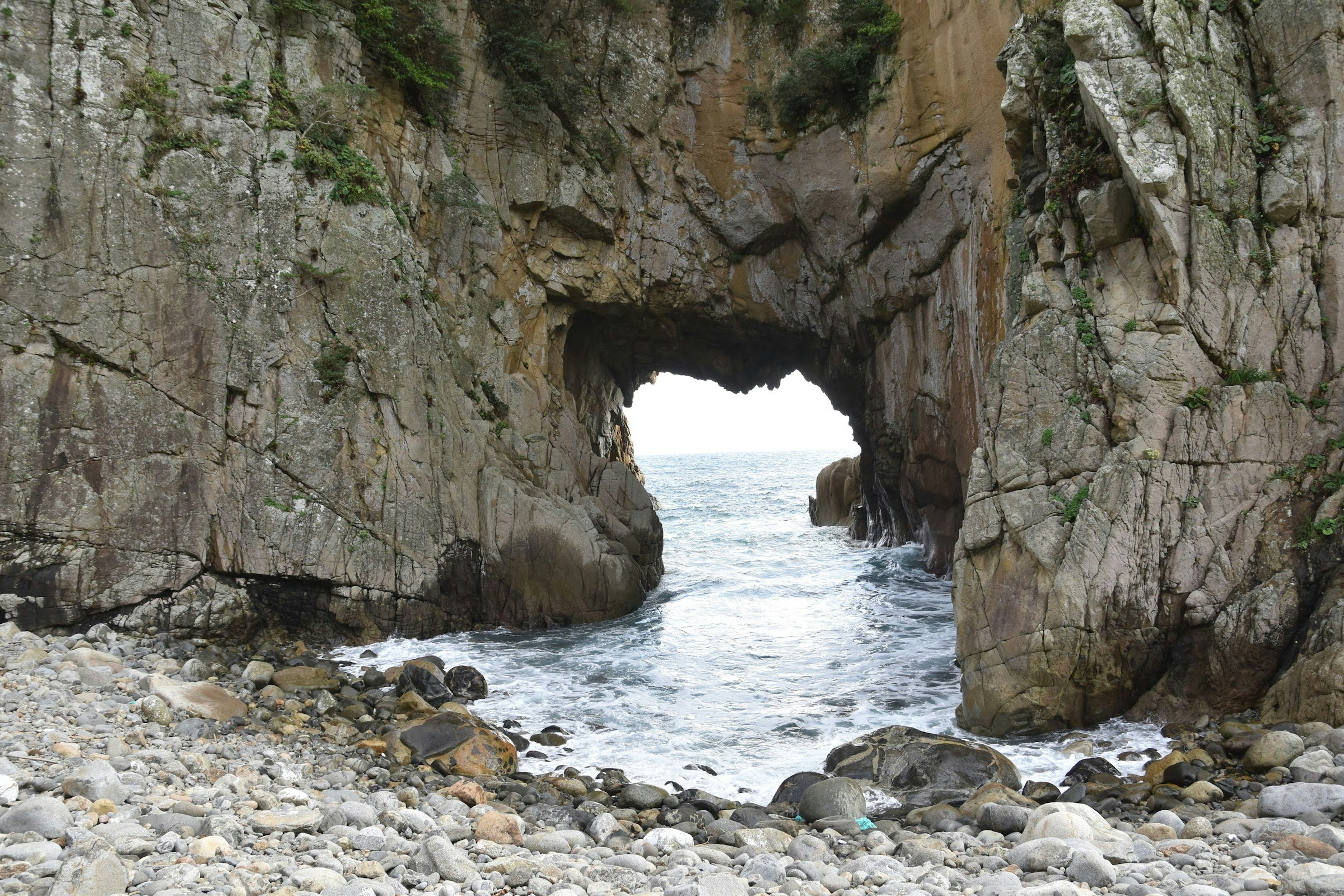 Scenic view of a rock formation with a natural arch overlooking the ocean