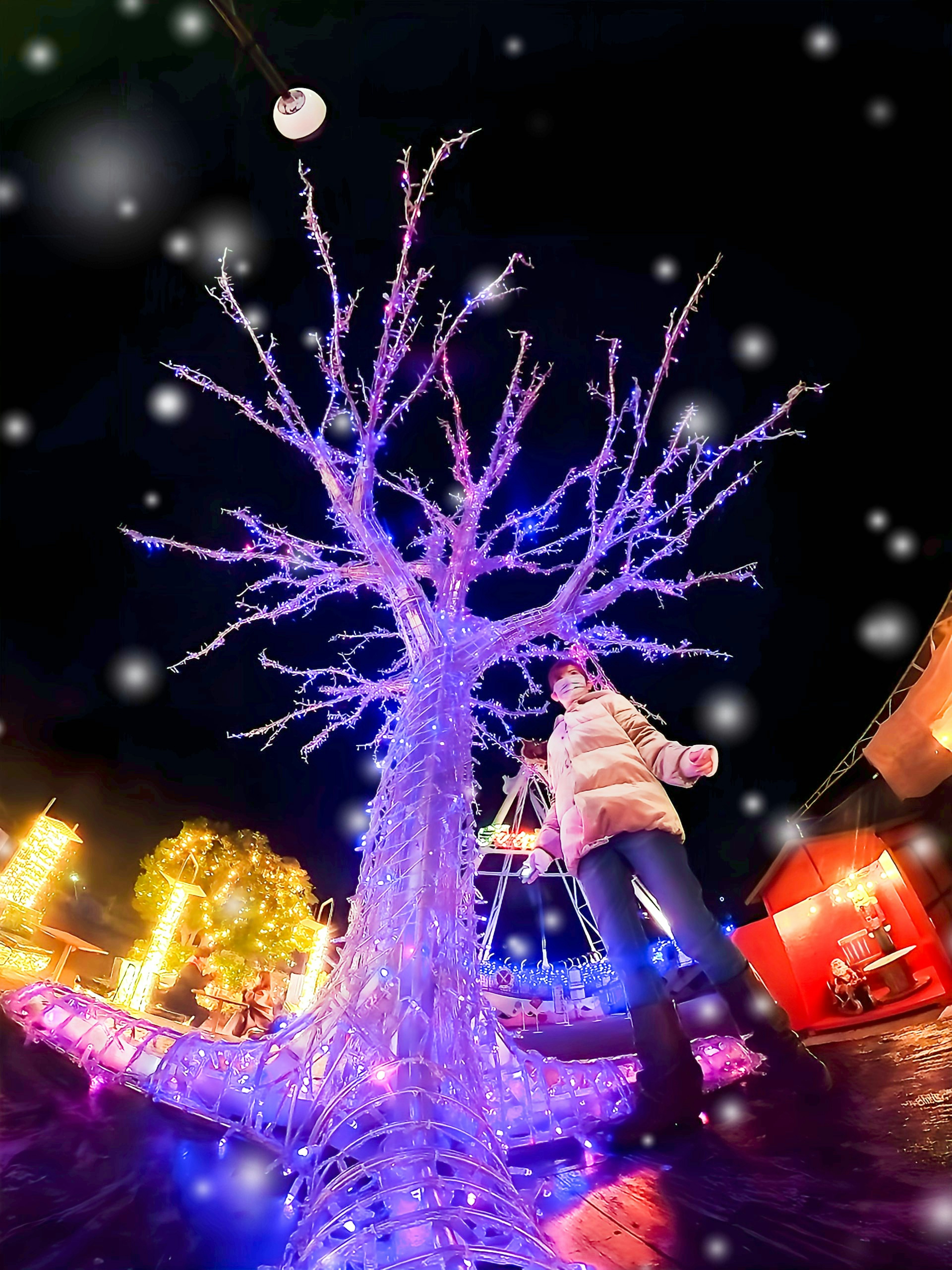 Albero illuminato con luci blu e viola su uno sfondo innevato