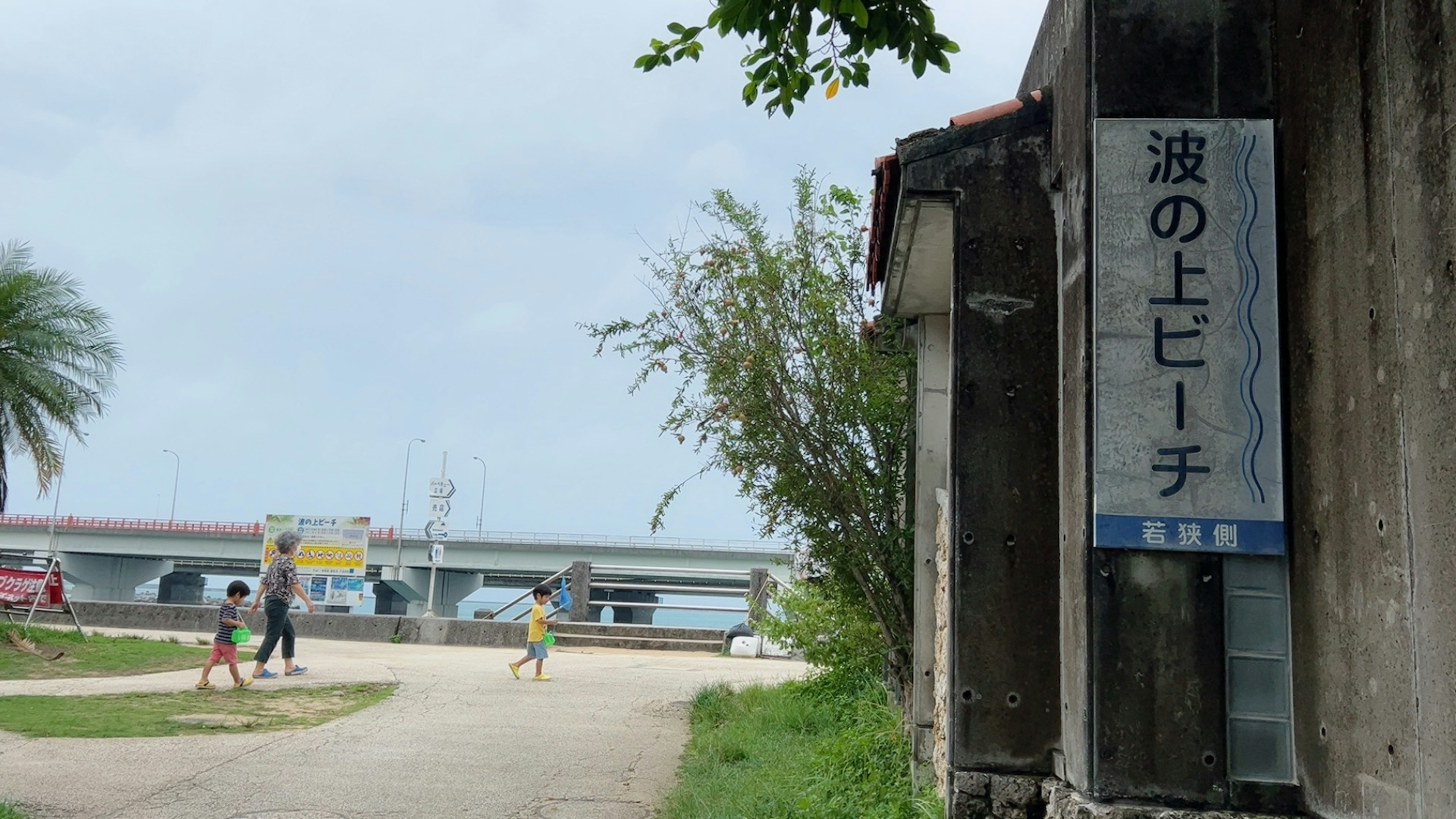 Children walking along a coastal path with an old building sign