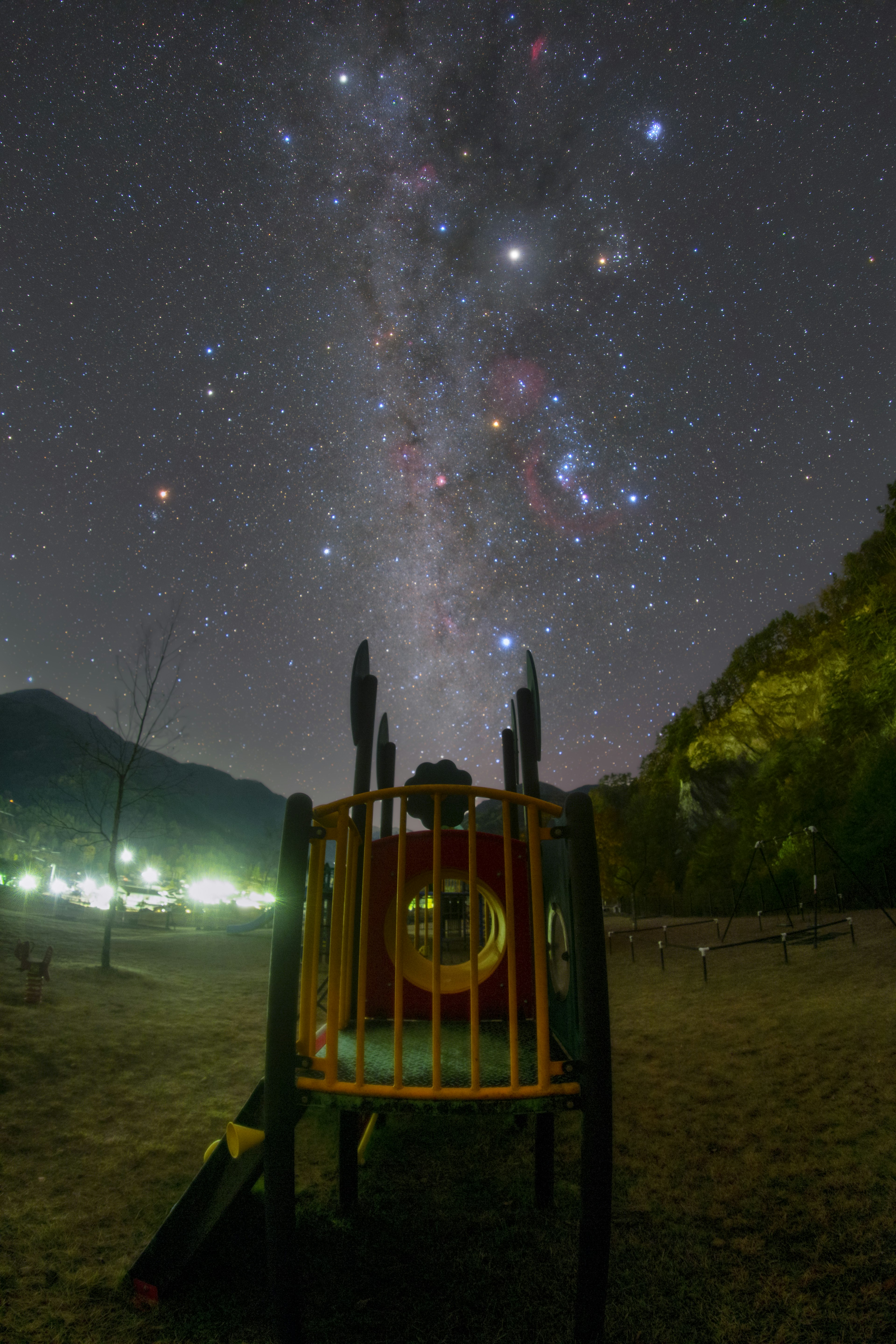 夜空に広がる銀河と遊具が映る風景