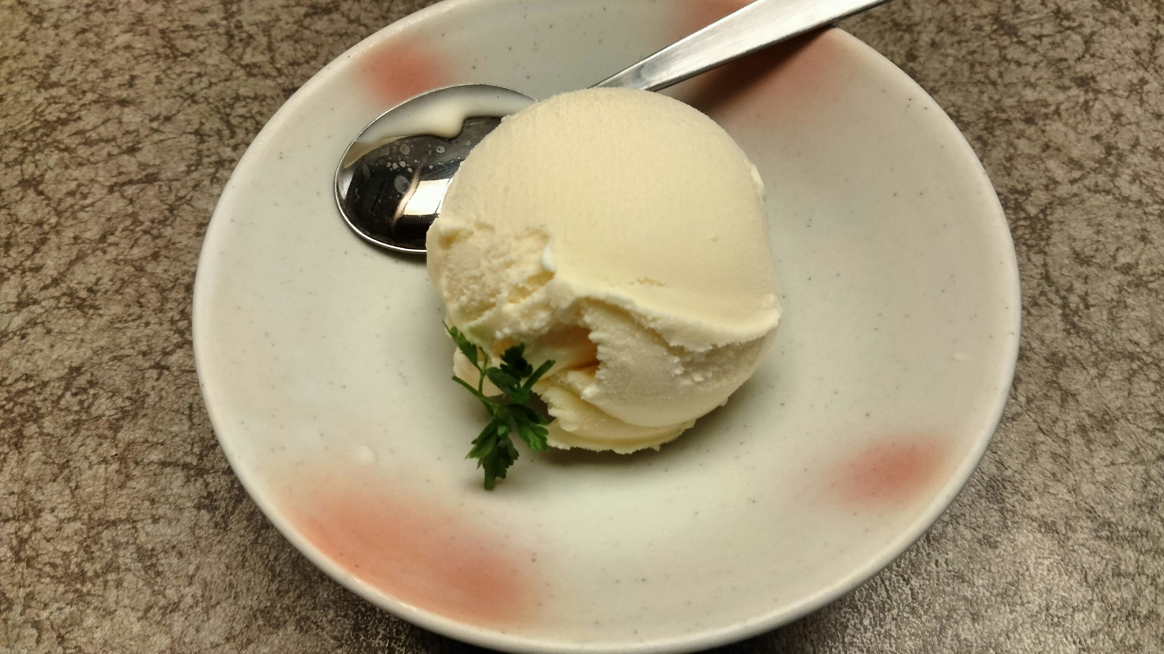 Cream-colored ice cream on a white plate with a spoon