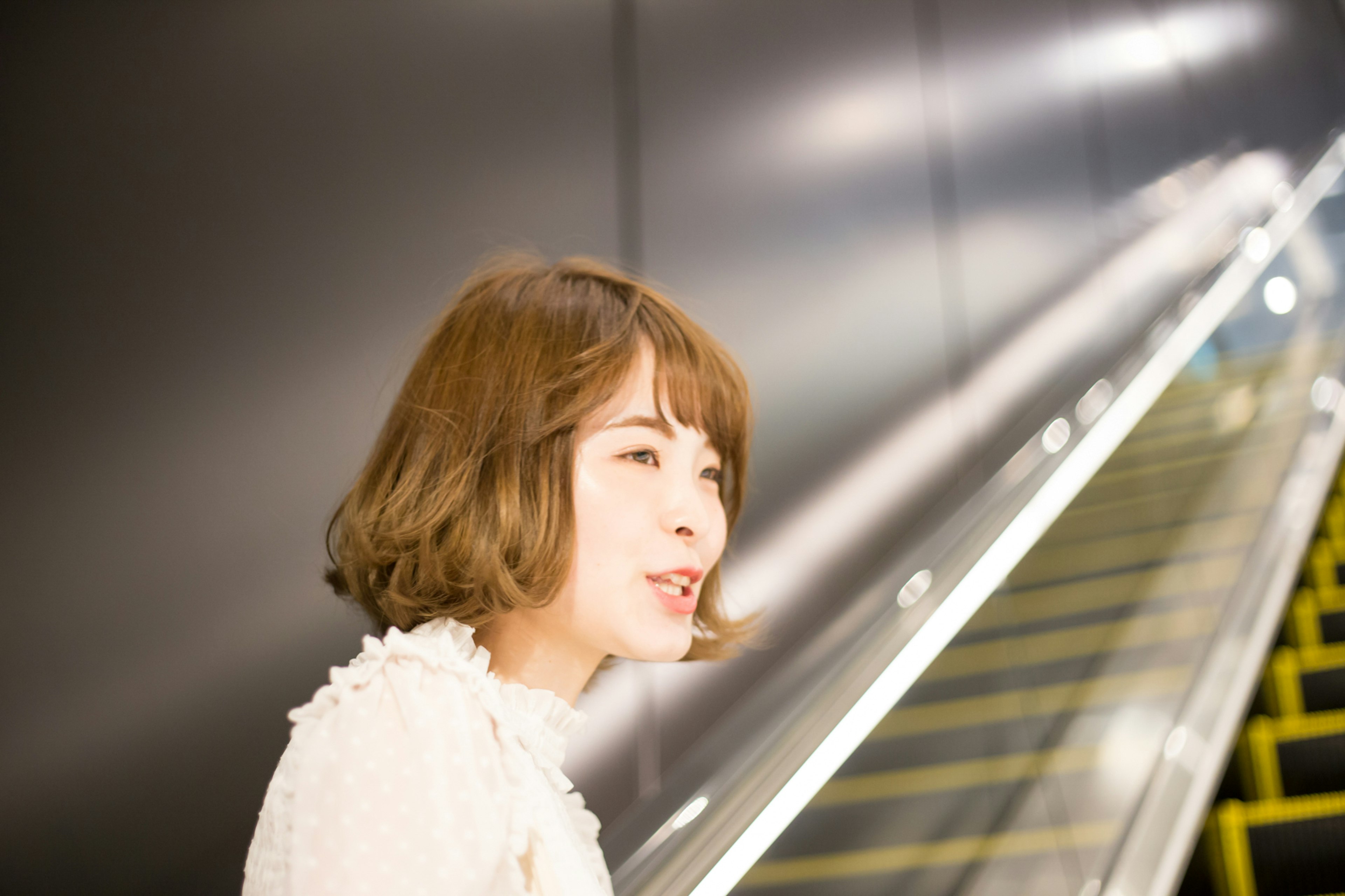 Una mujer sonriendo frente a una escalera mecánica