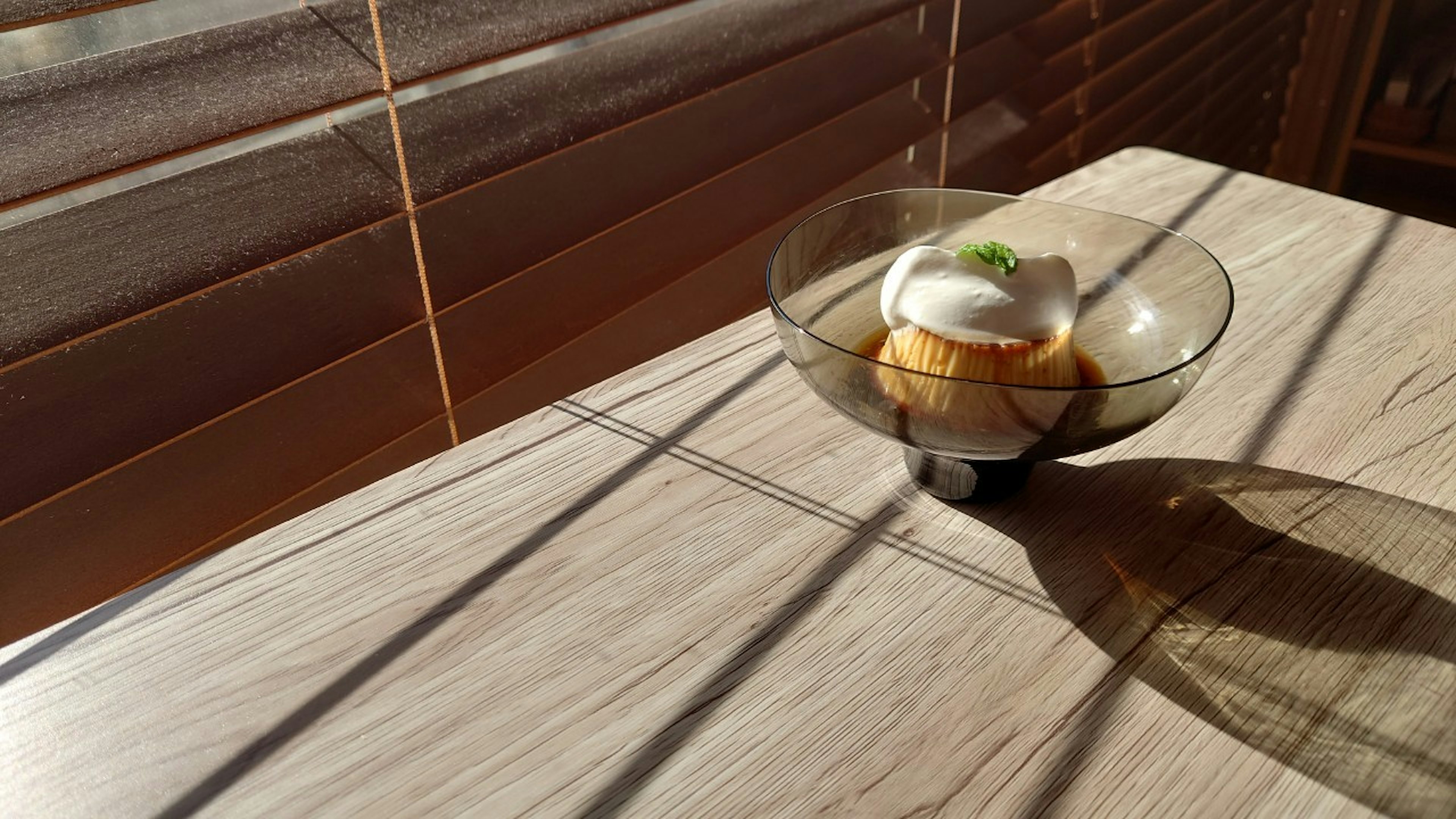 Tazón de helado sobre una mesa de madera con sombras de luz solar