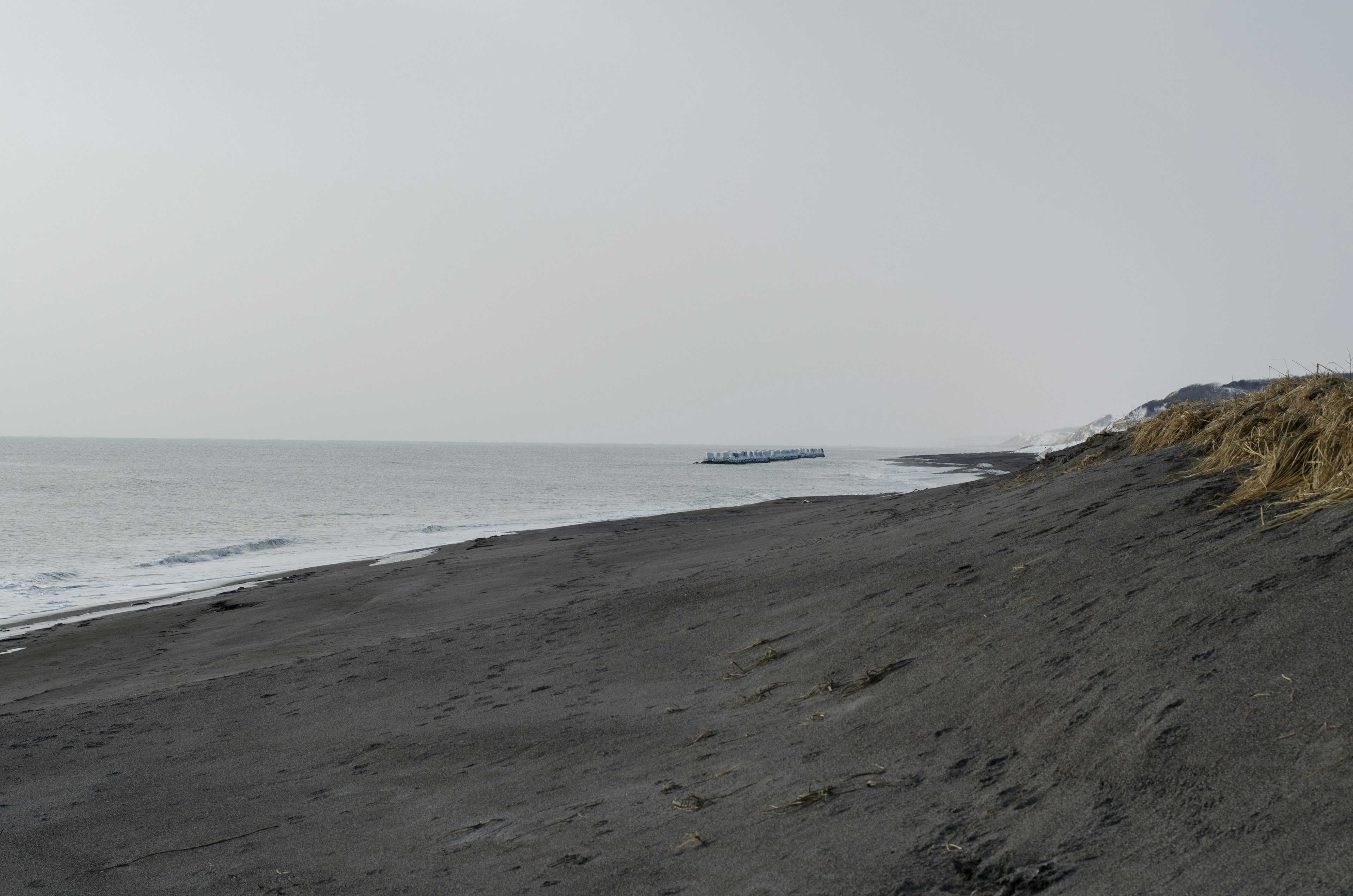 Black sandy beach with calm sea view