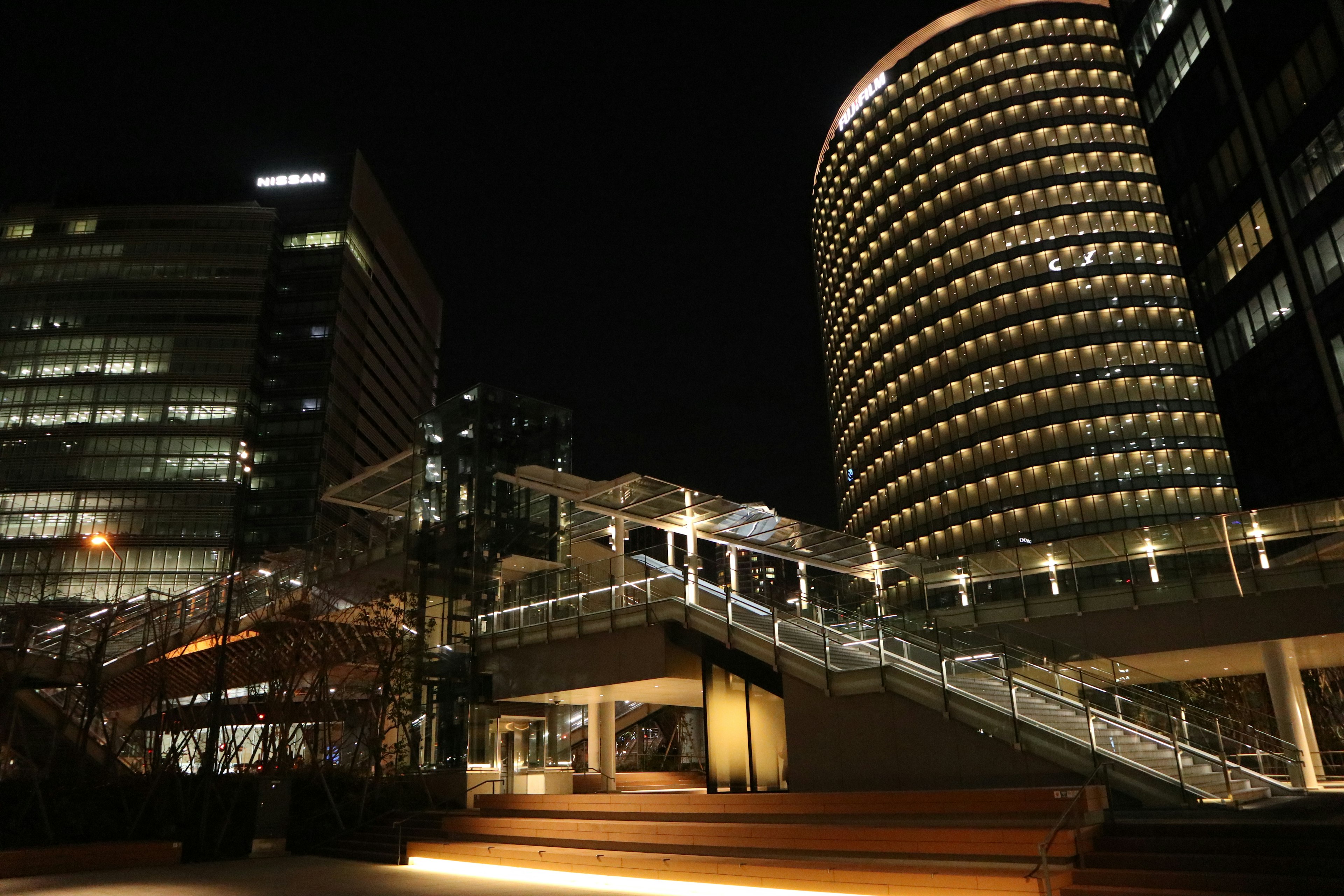 Nighttime cityscape featuring tall buildings and illuminated stairs