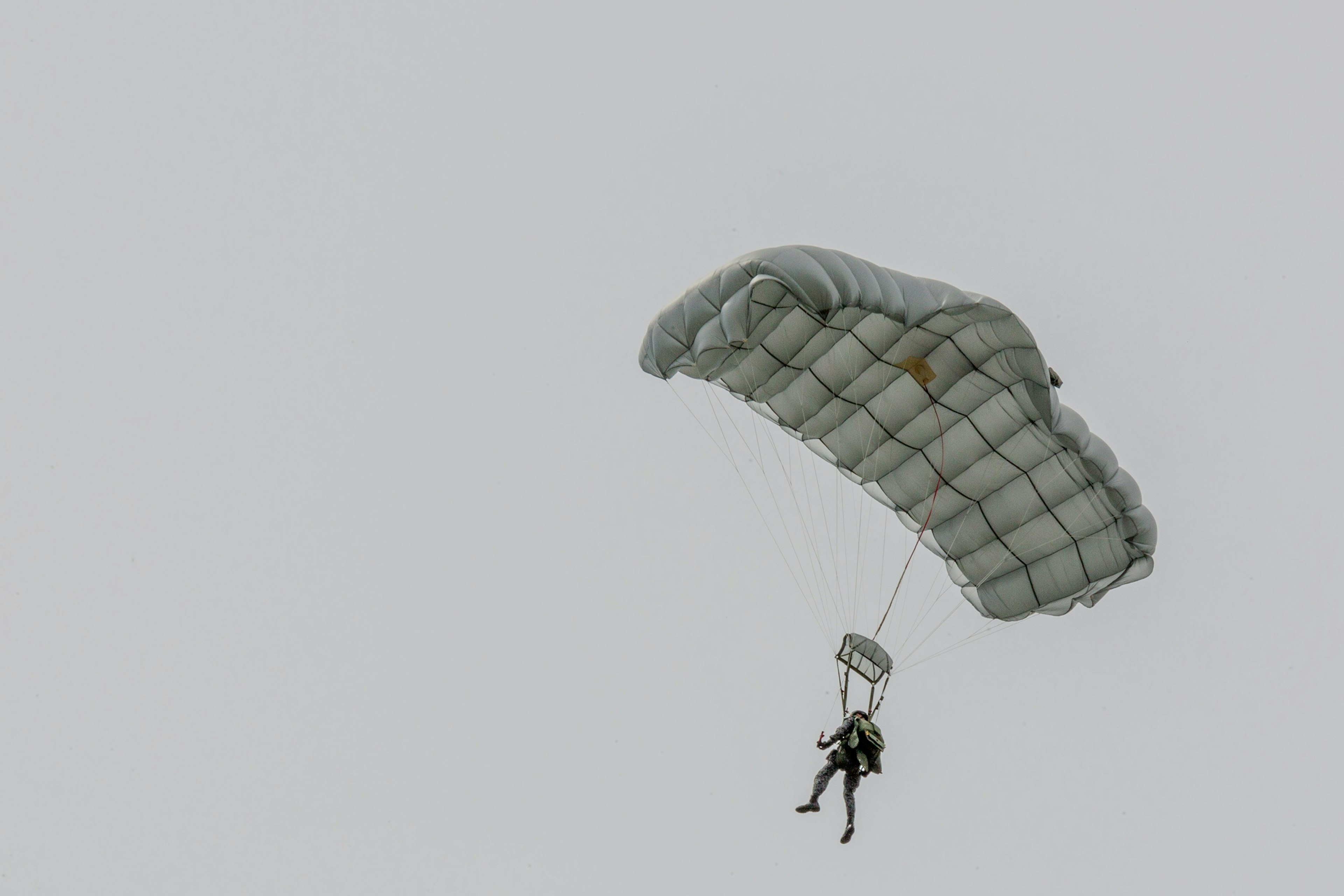 Una persona descendiendo con un paracaídas contra un cielo nublado