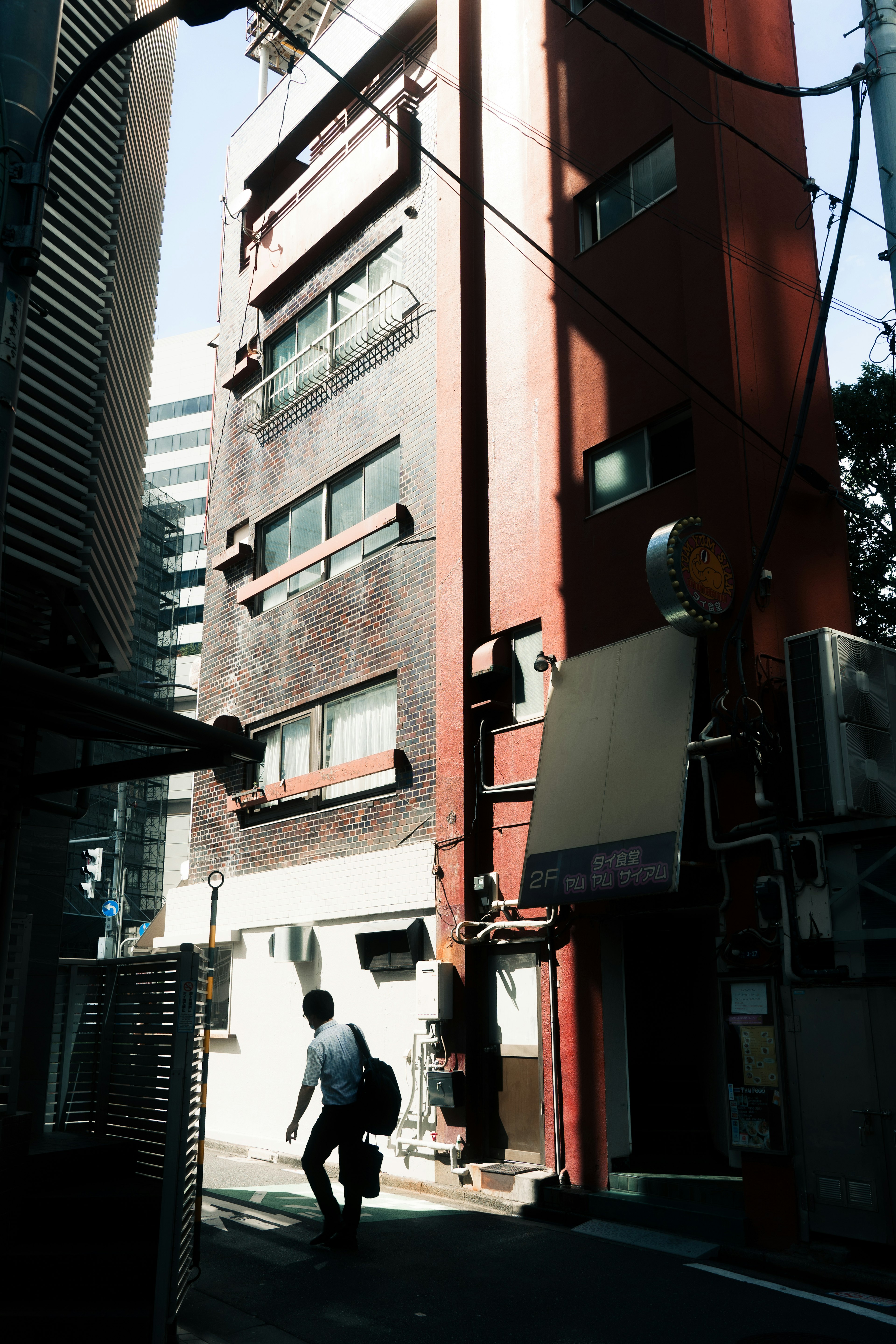 A person walking in front of a building with a red facade