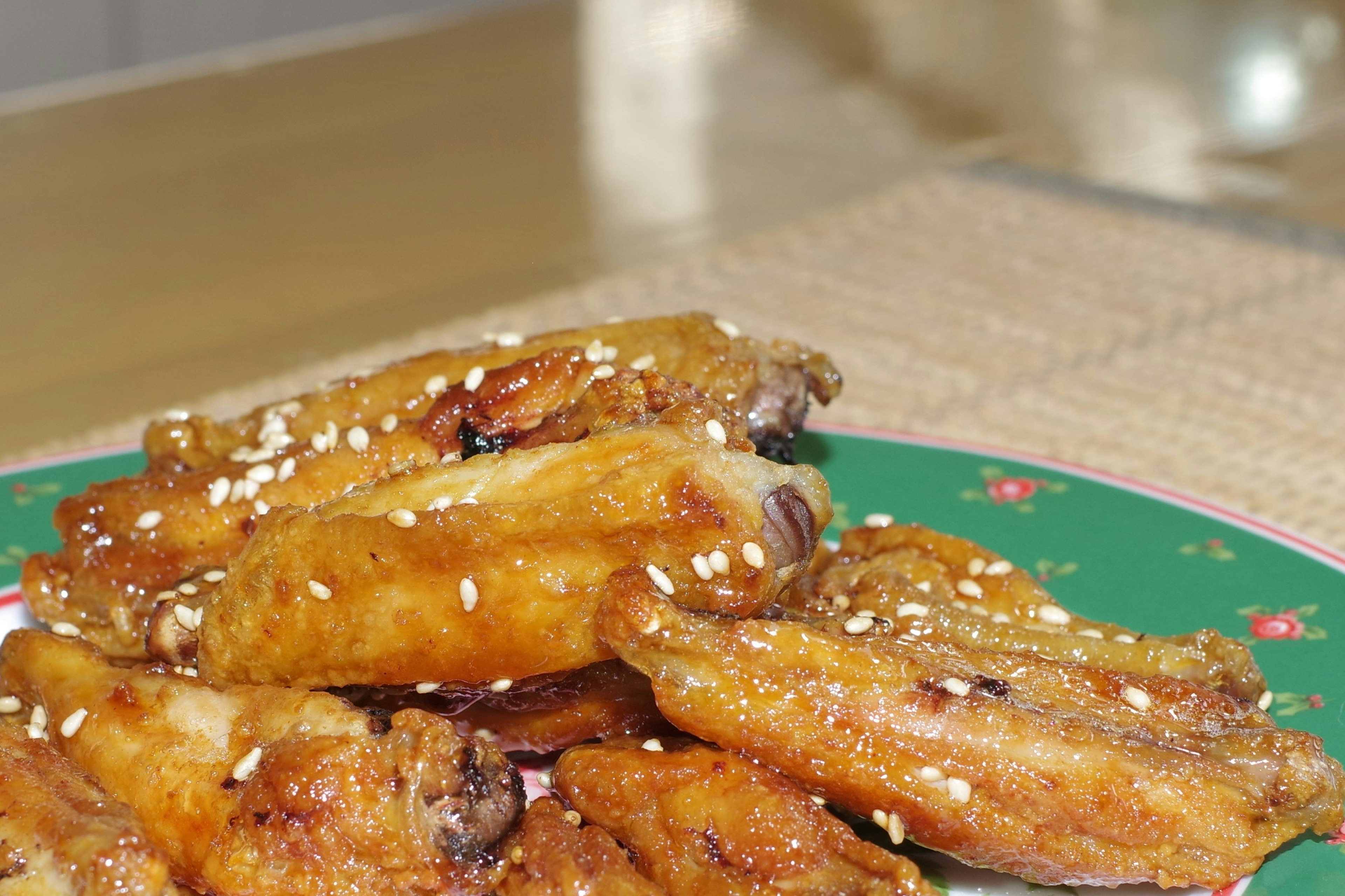 Fried chicken wings garnished with sesame seeds on a green plate