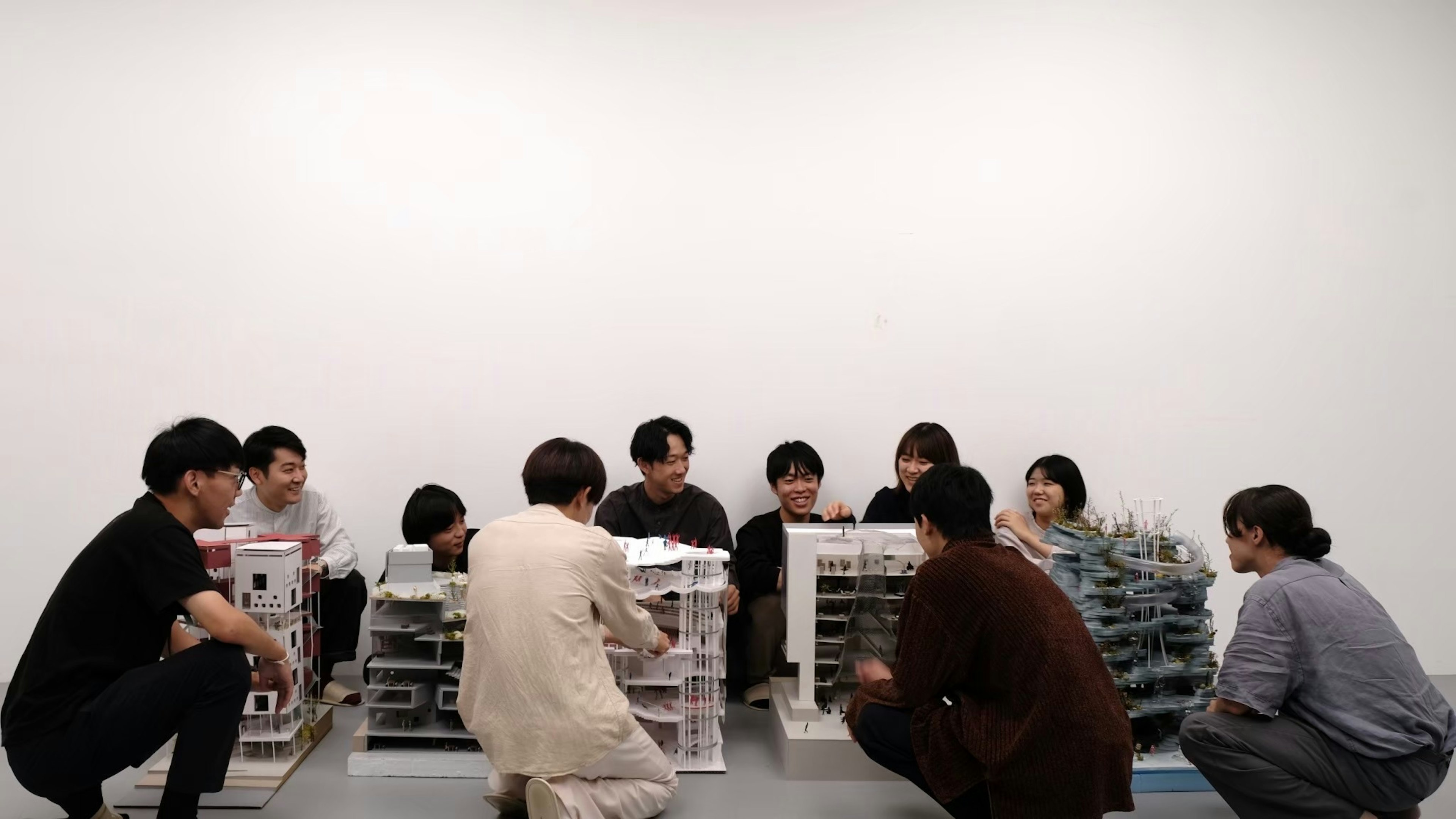 Group of people sitting around a table examining models in an art workshop