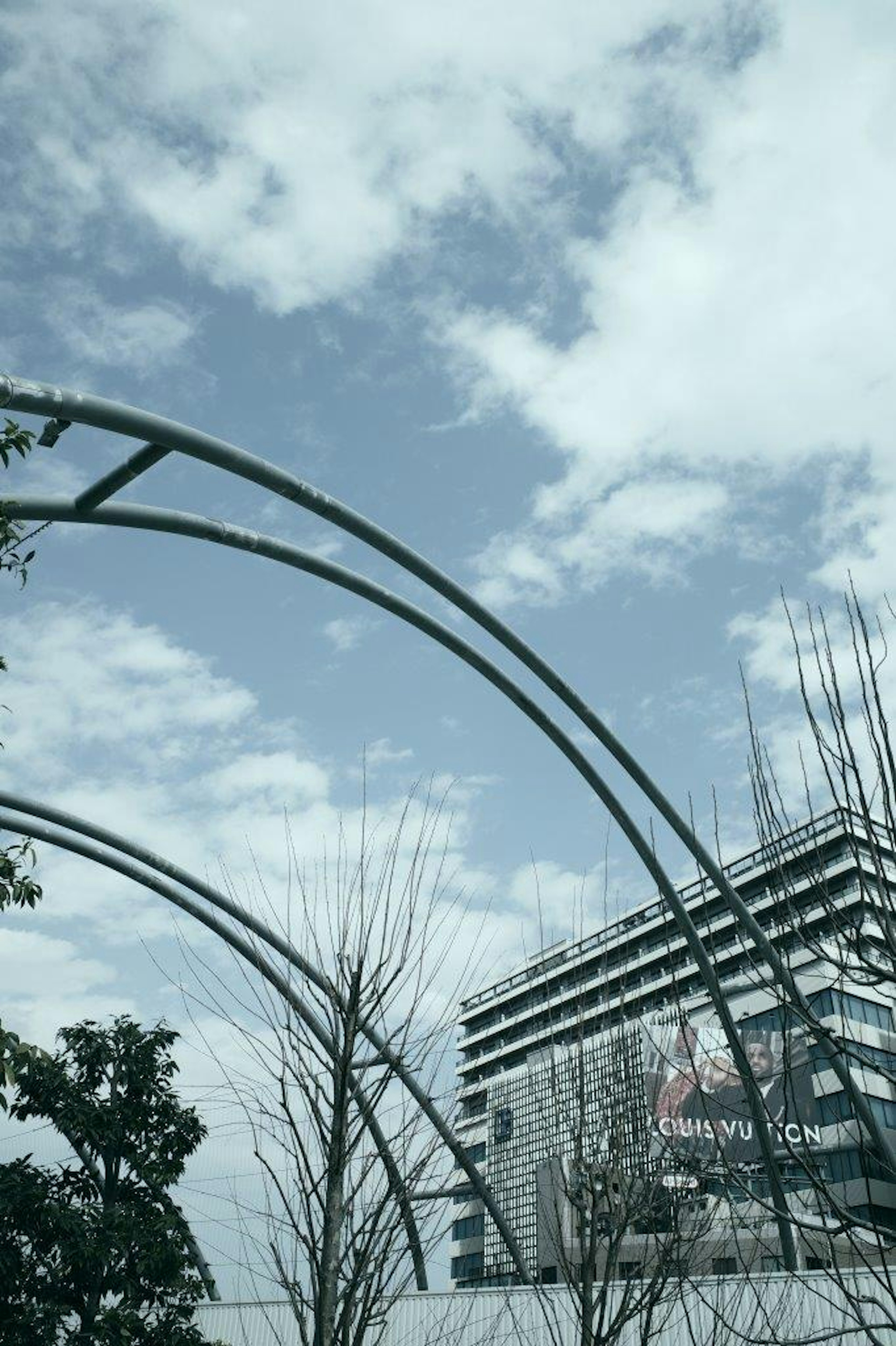 Lanskap dengan struktur melengkung dan gedung di bawah langit biru