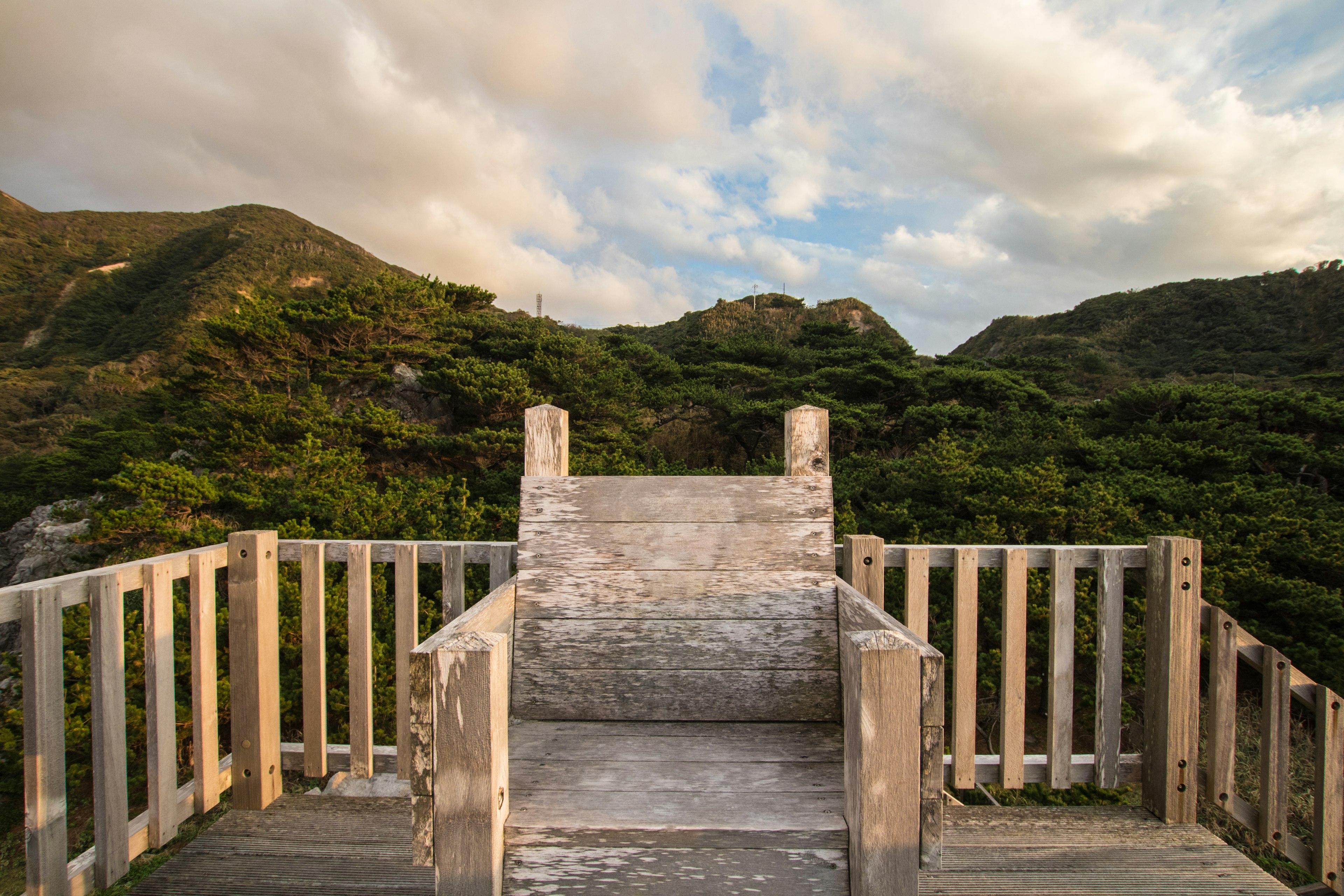 Chaise en bois sur un point de vue entouré de verdure luxuriante et de montagnes