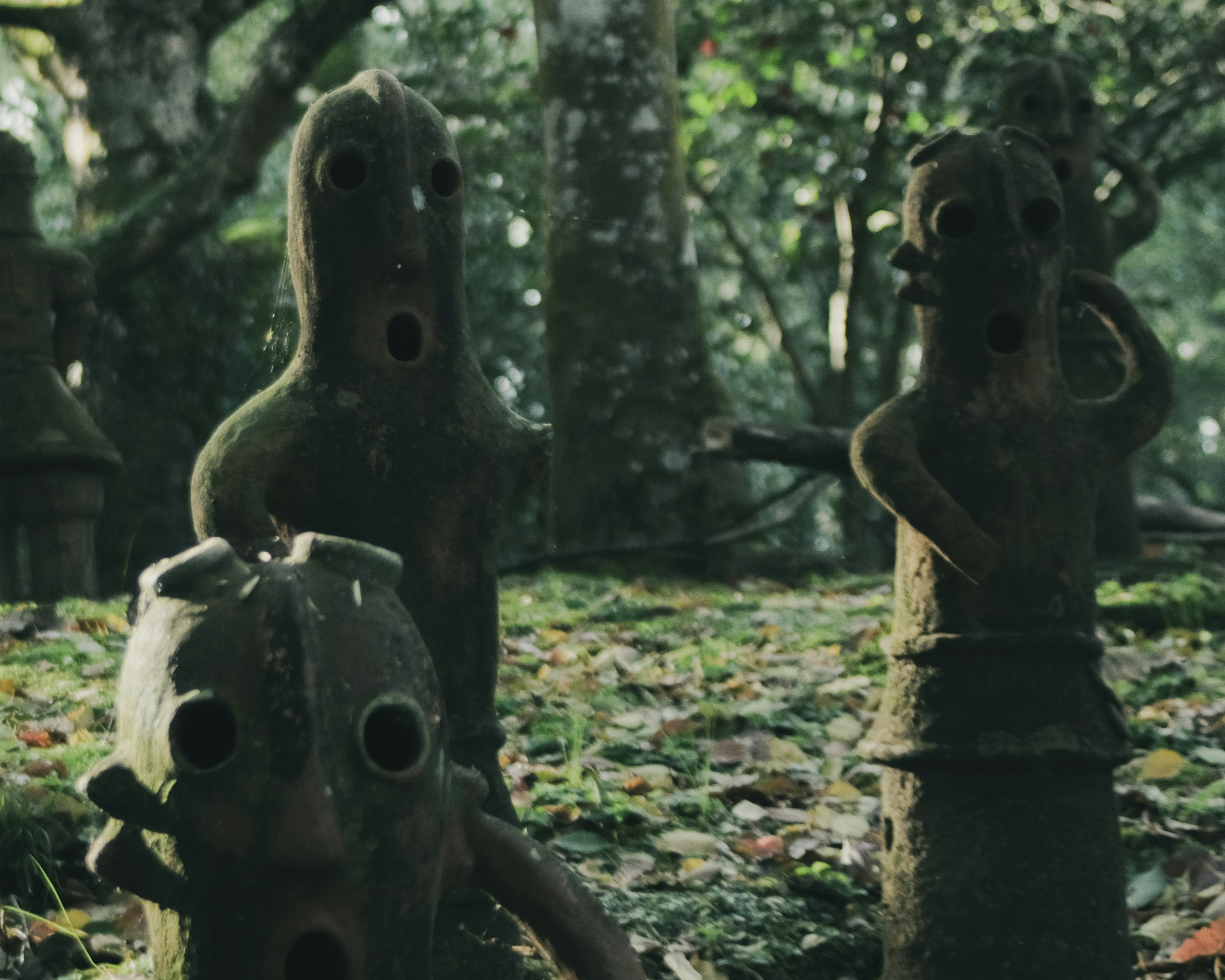 Sculptures anciennes avec des visages creux dans un cadre forestier