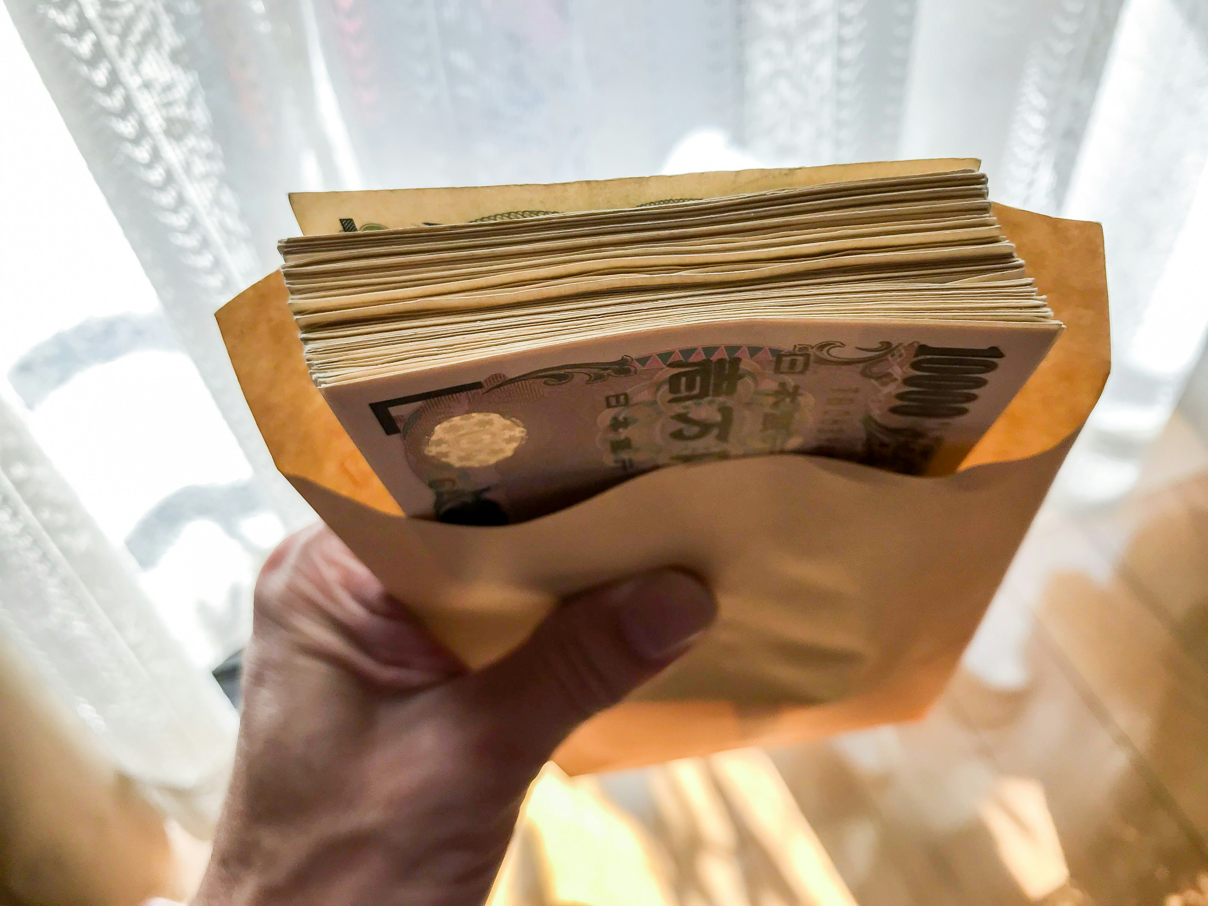 A hand holding an envelope containing cash