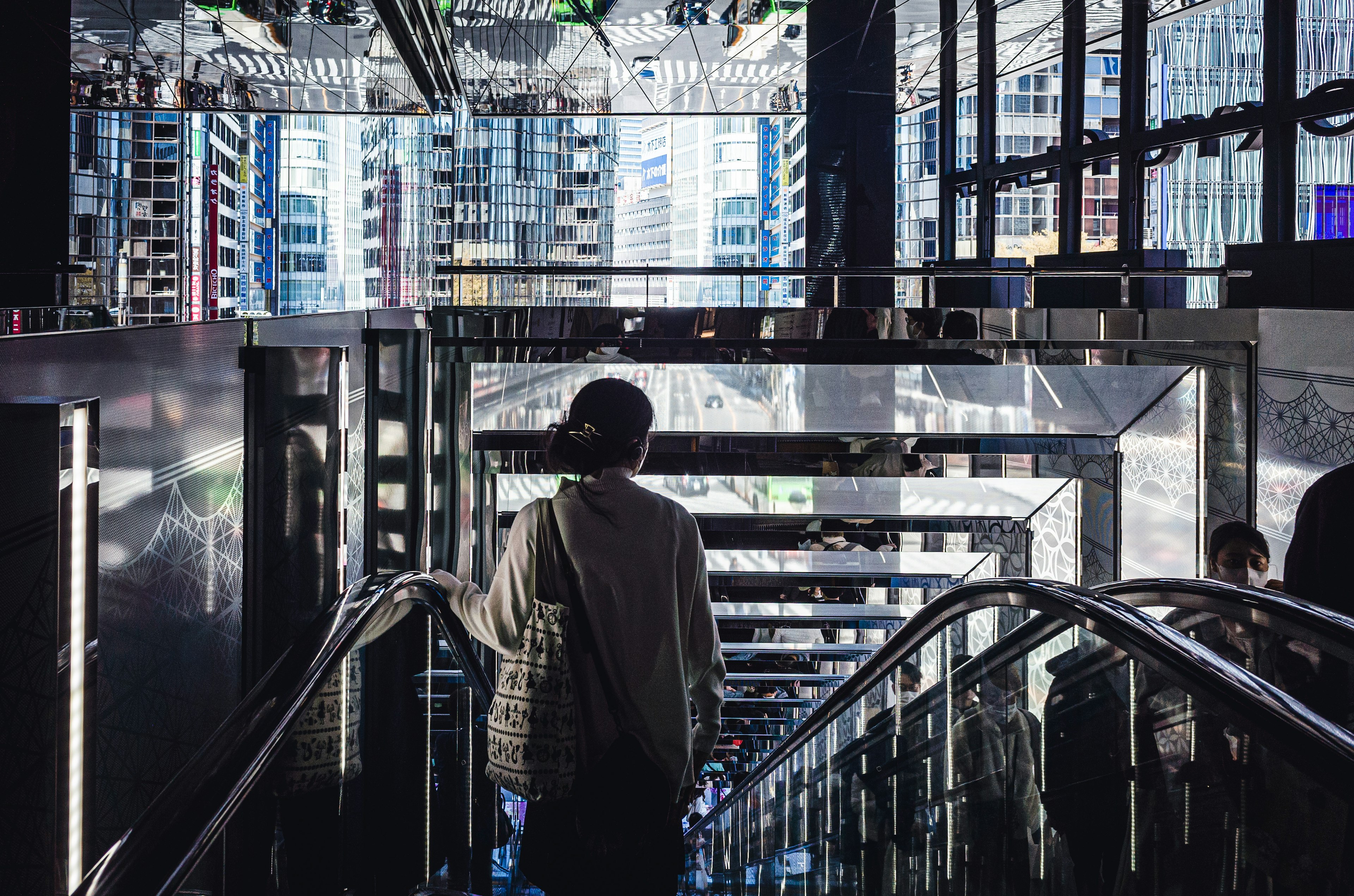 Personne descendant un escalator dans un bâtiment moderne avec des surfaces réfléchissantes