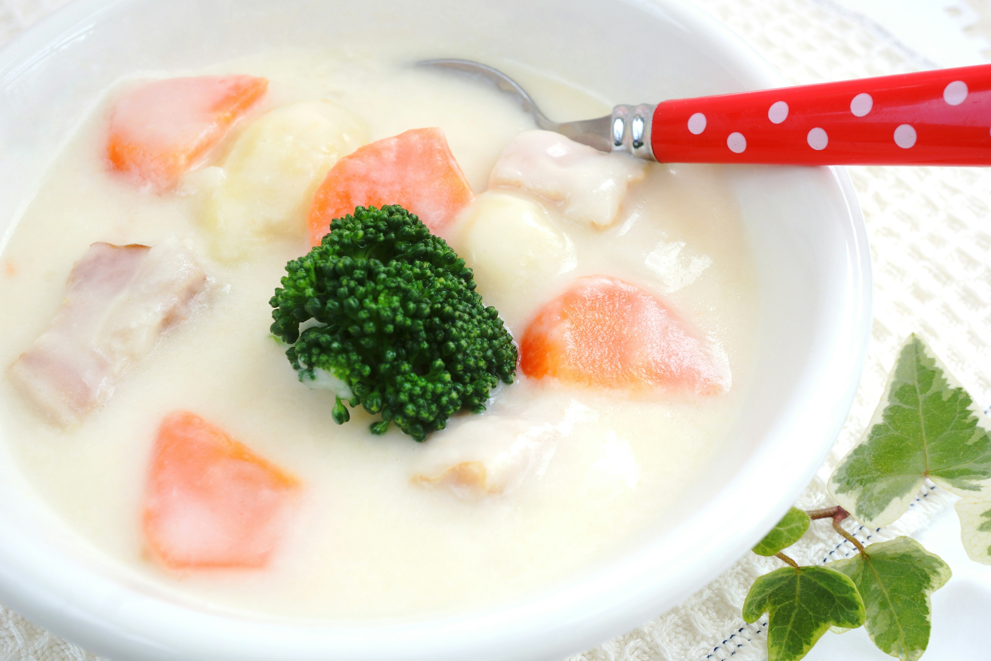 Sopa cremosa de pollo y verduras con brócoli y zanahorias en un tazón blanco