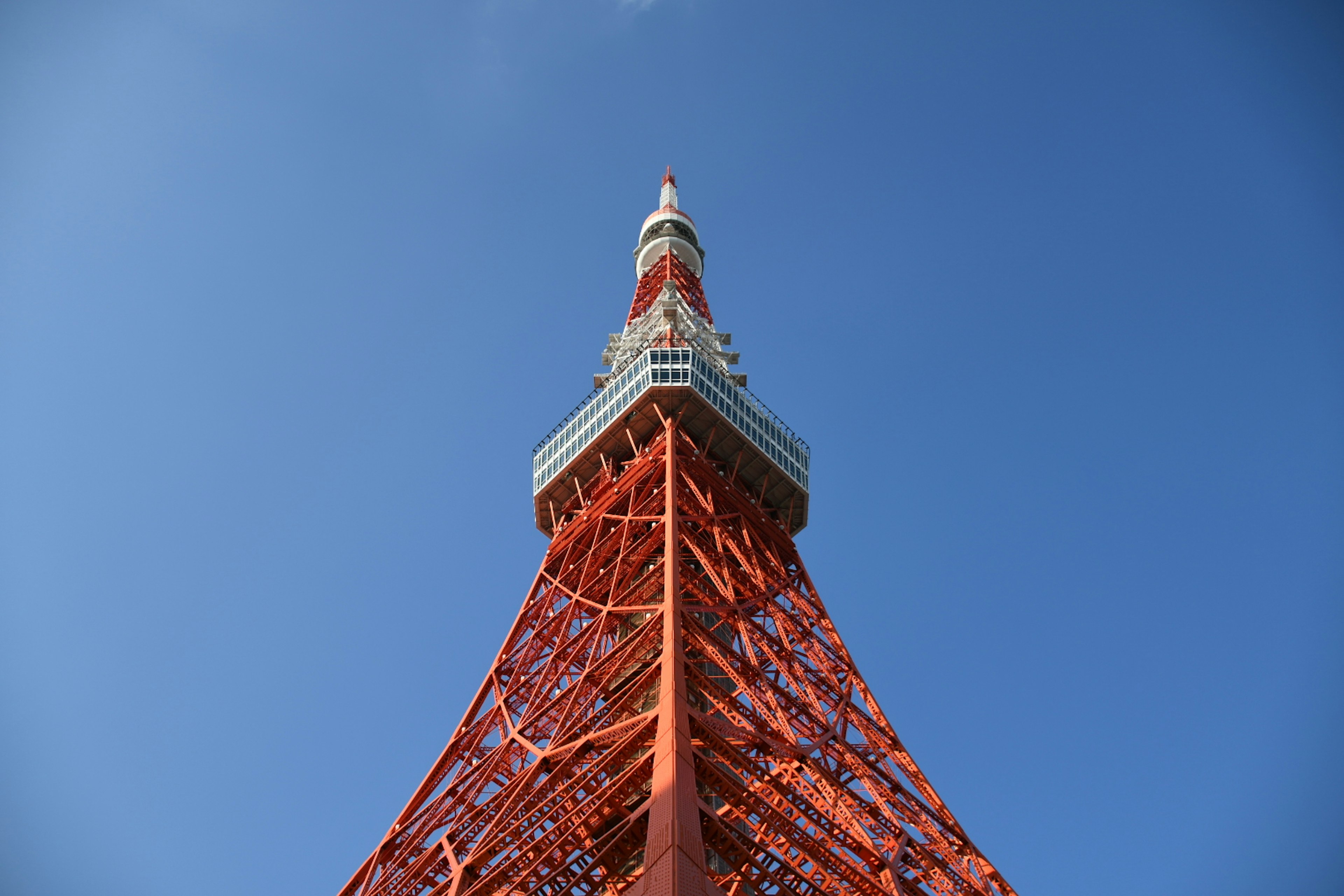 東京タワーの上部を見上げる視点で青空の下に立つ