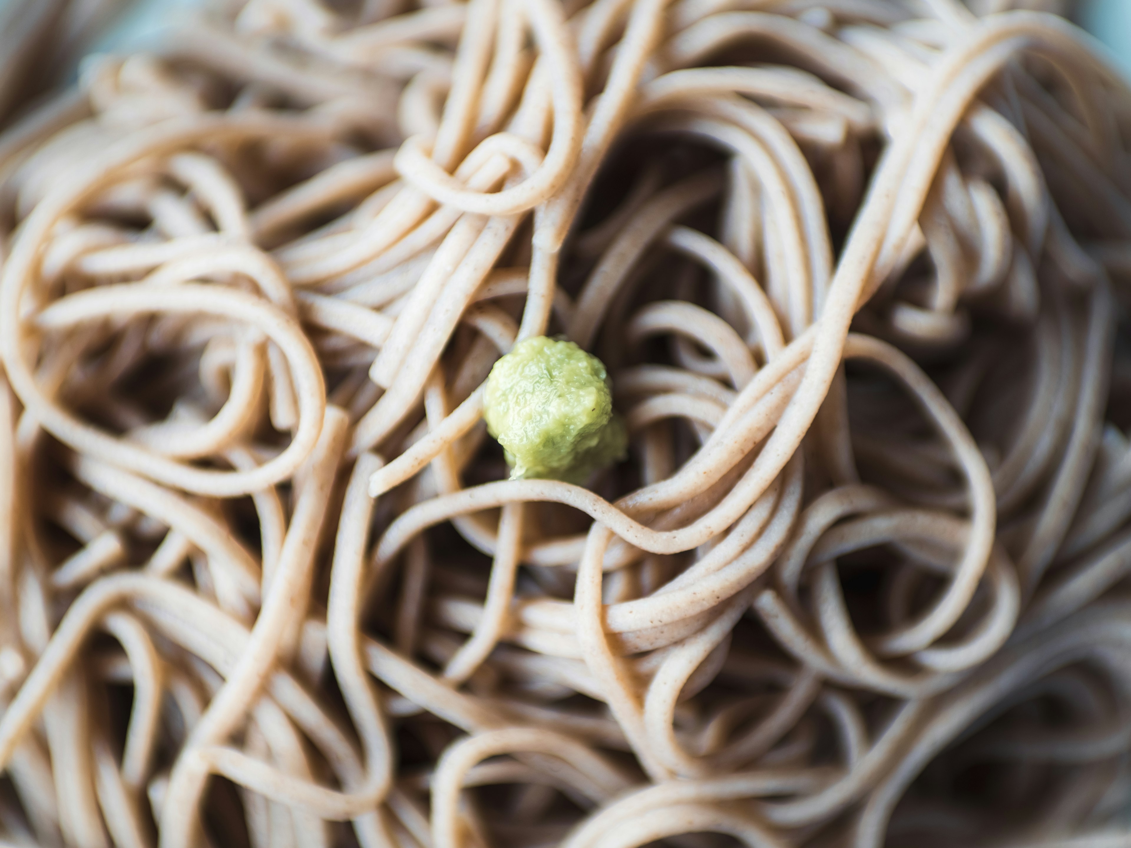 Nahaufnahme von Soba-Nudeln mit grünem Wasabi darauf