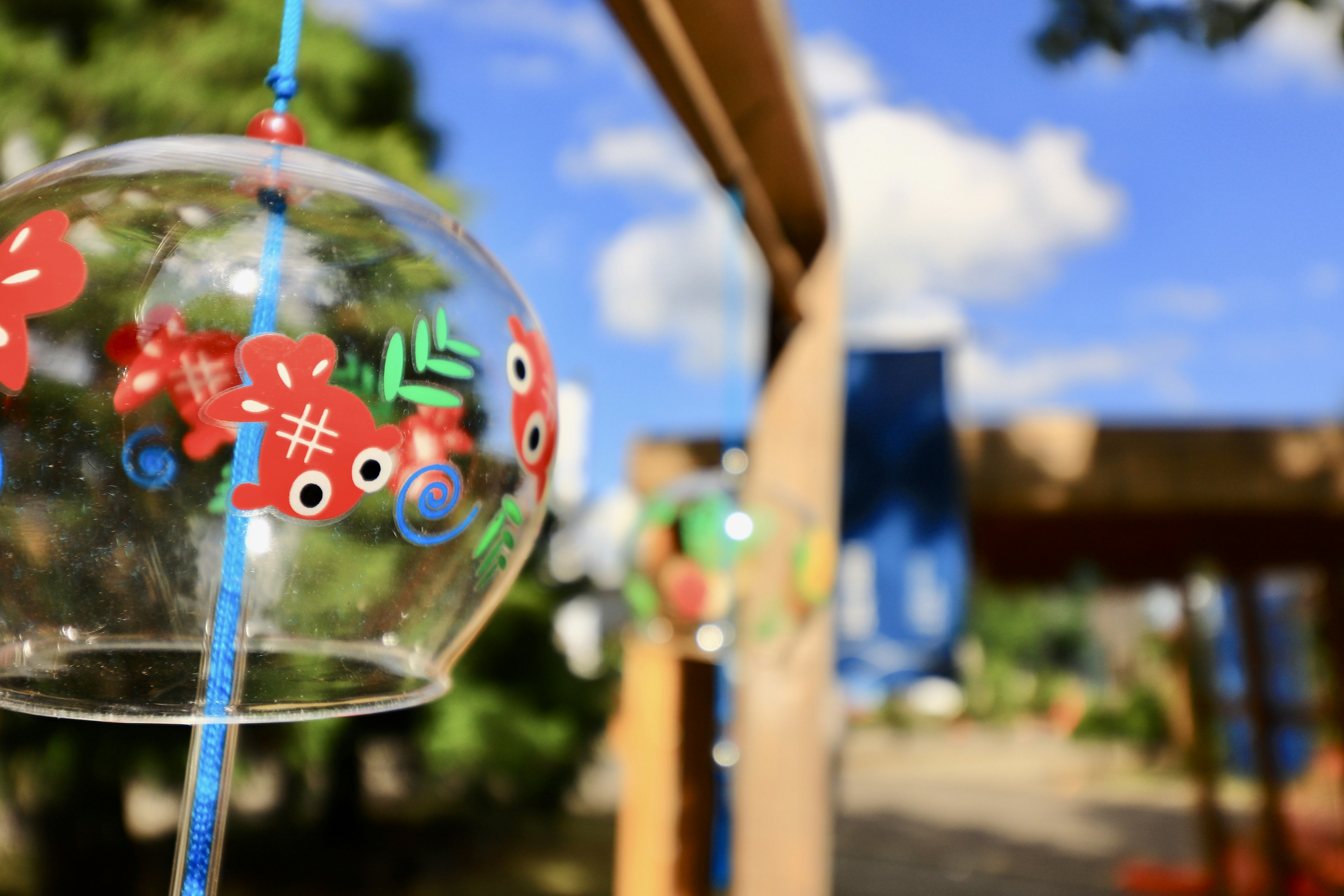 Bunte Windglocke hängt in einer malerischen Außenumgebung mit blauem Himmel und Bäumen