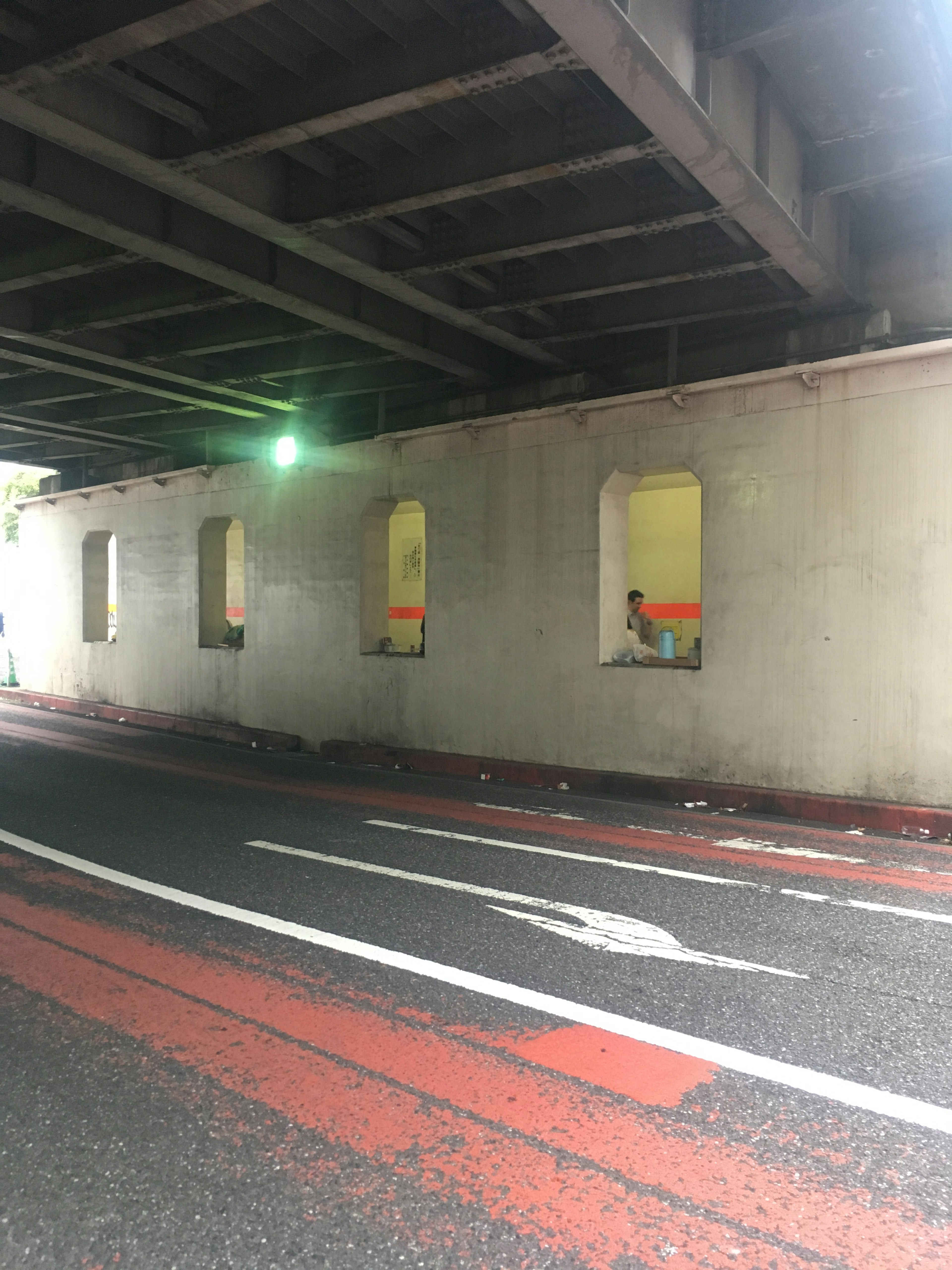 Wall with windows under a road featuring green light