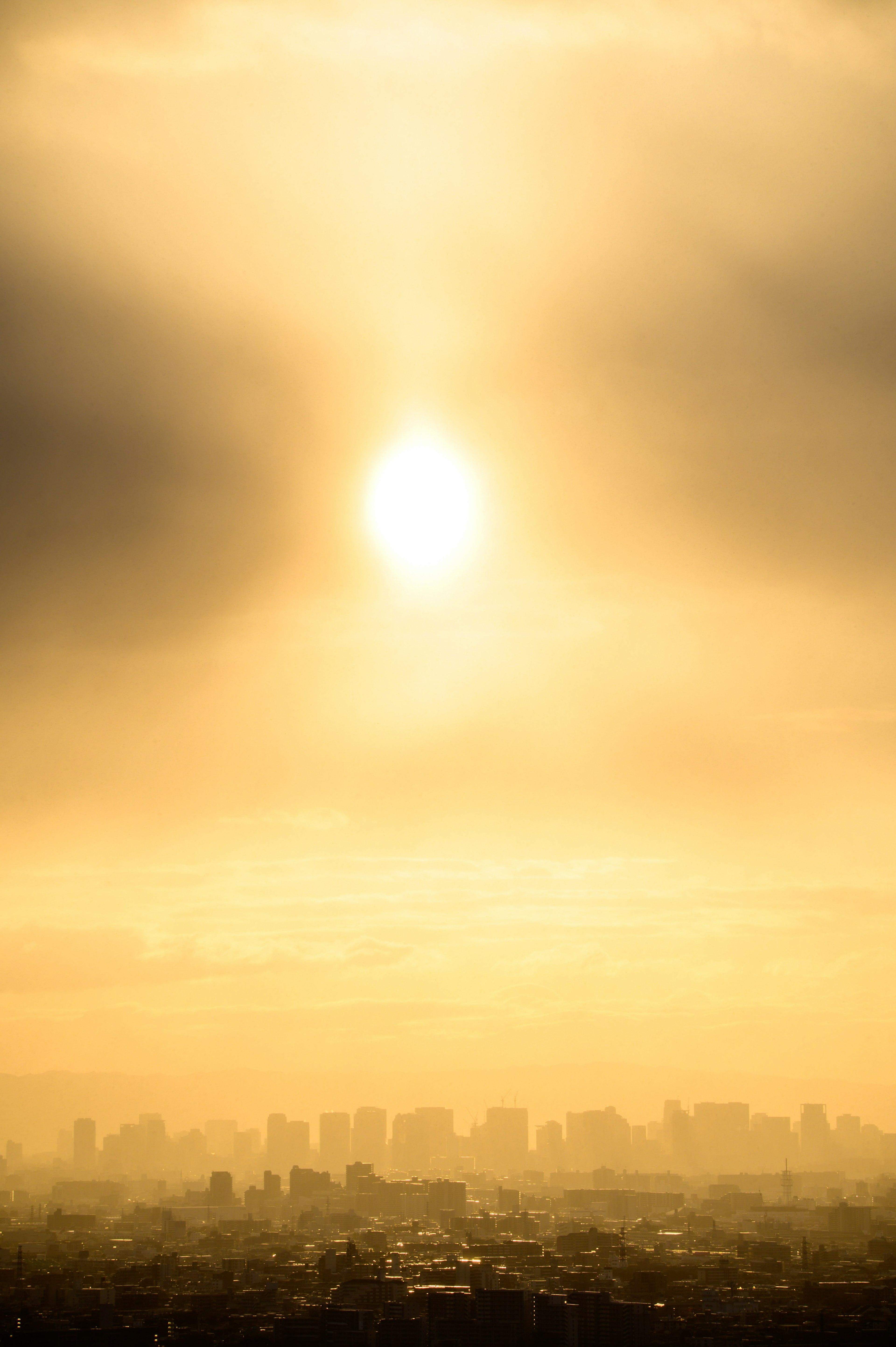 Glowing sun in a hazy sky with city silhouette