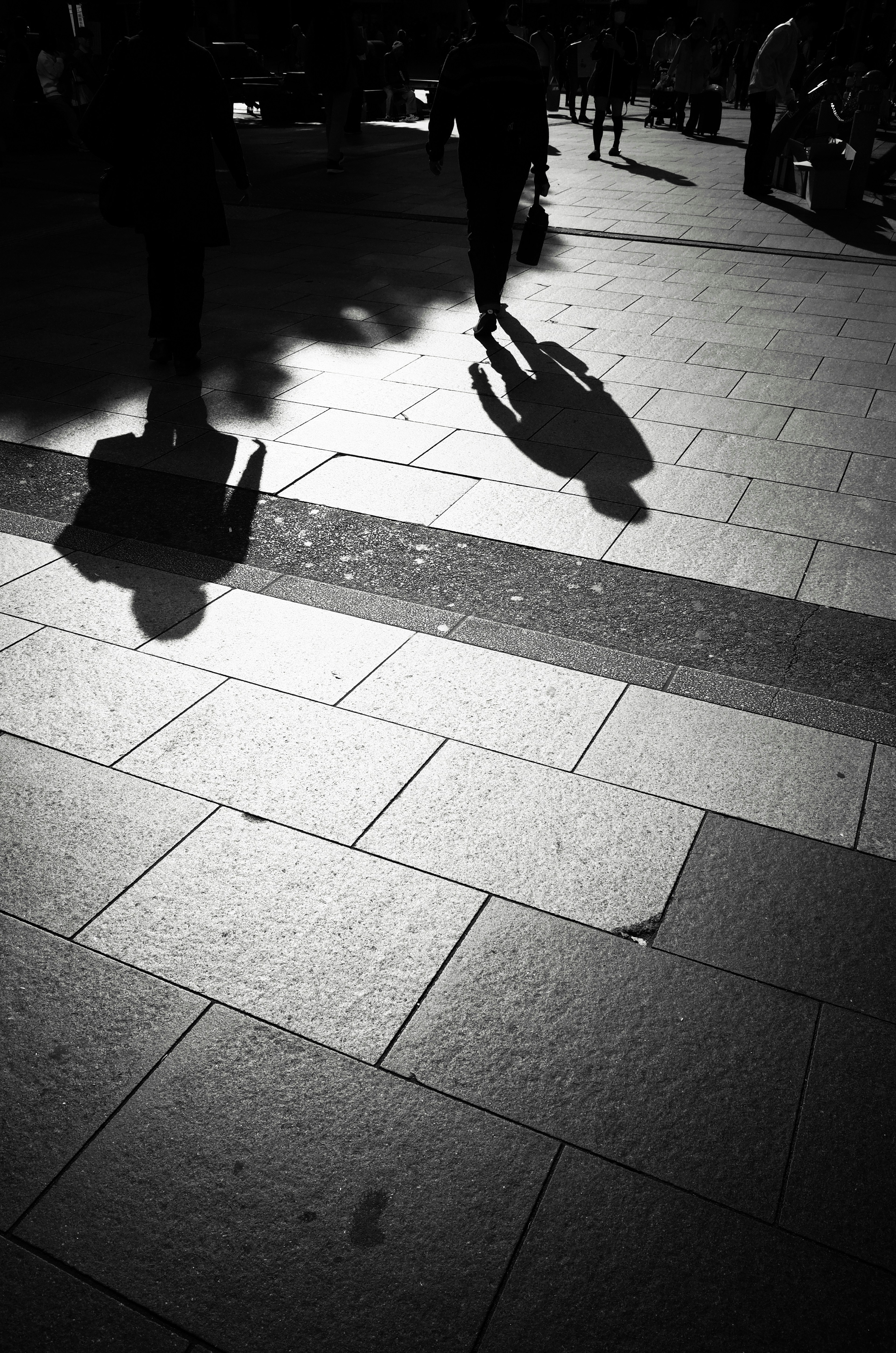 Scène de rue en noir et blanc avec silhouettes et ombres