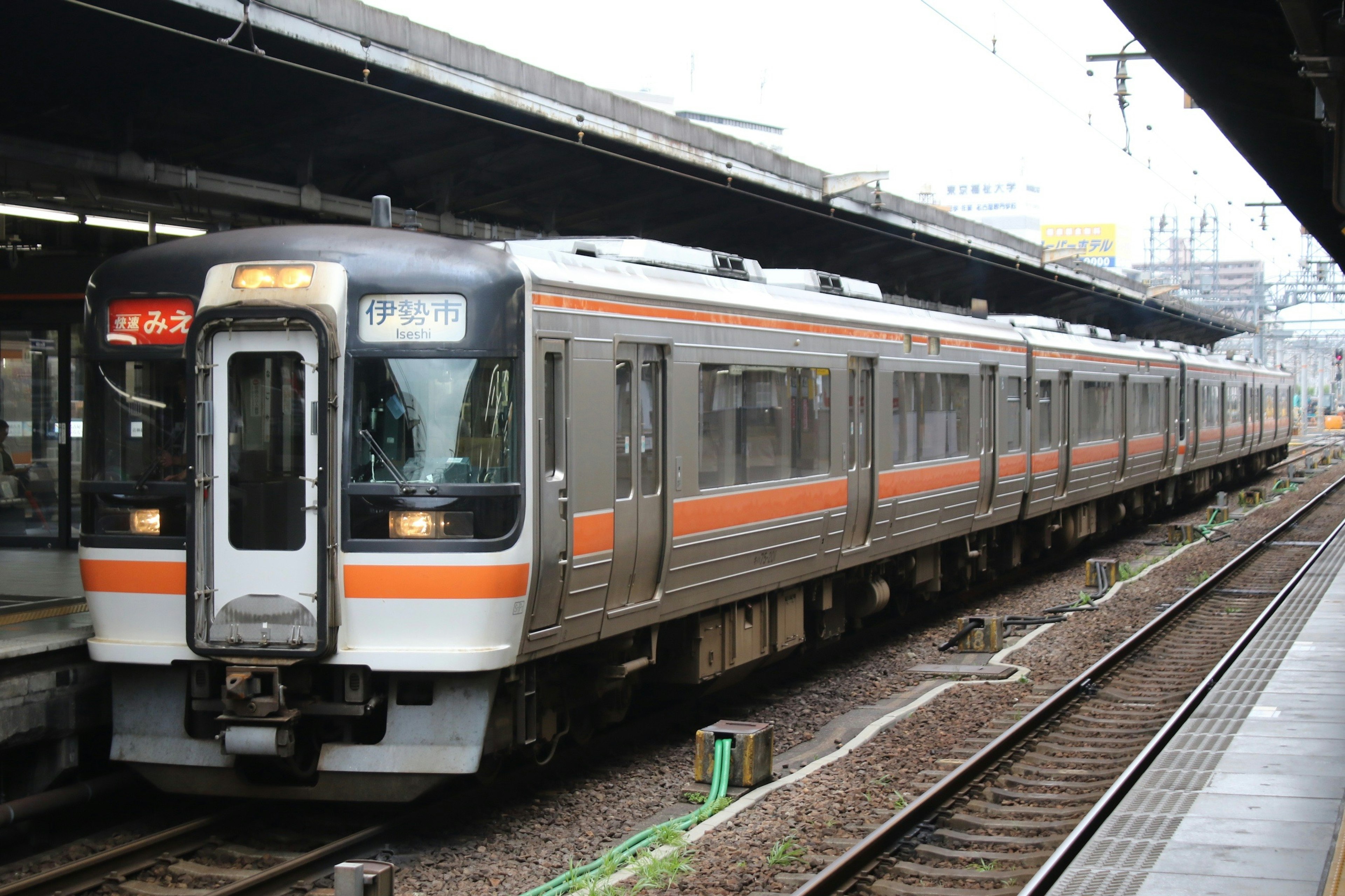 Tren japonés con distintivas franjas naranjas detenido en una estación