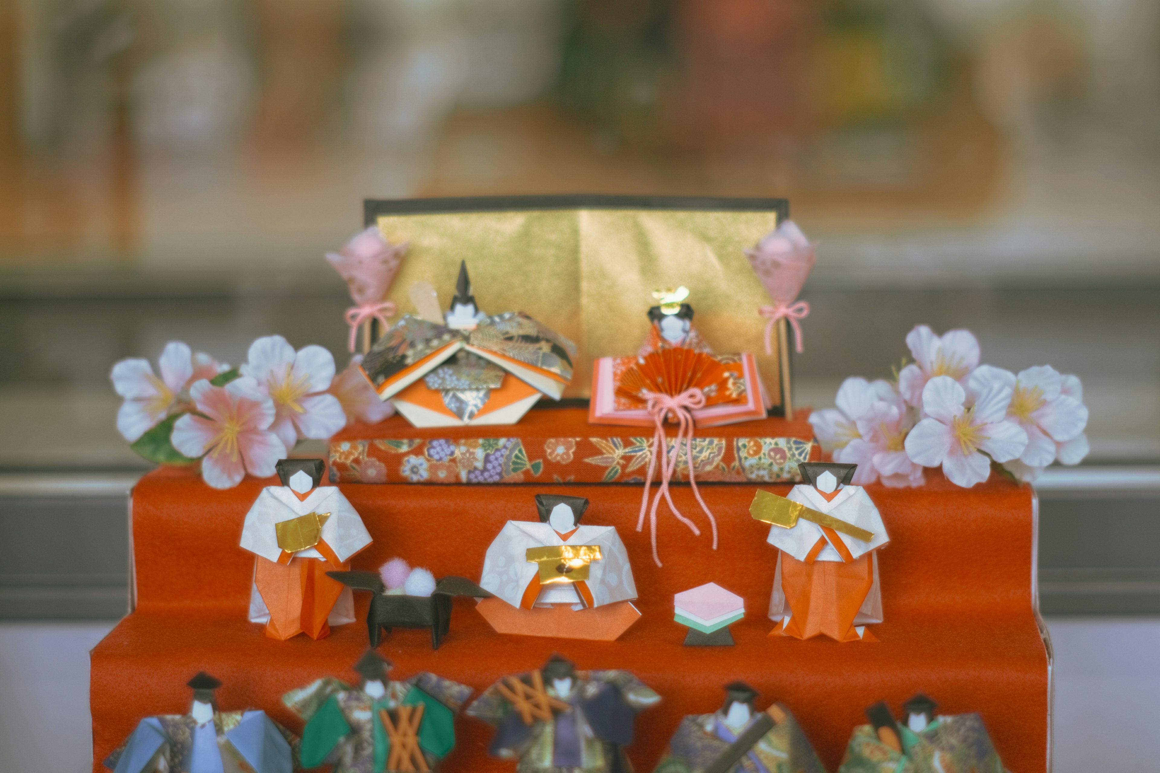 Ensemble de poupées Hina traditionnelles pour Hinamatsuri disposées sur un tissu rouge avec de belles fleurs de cerisier