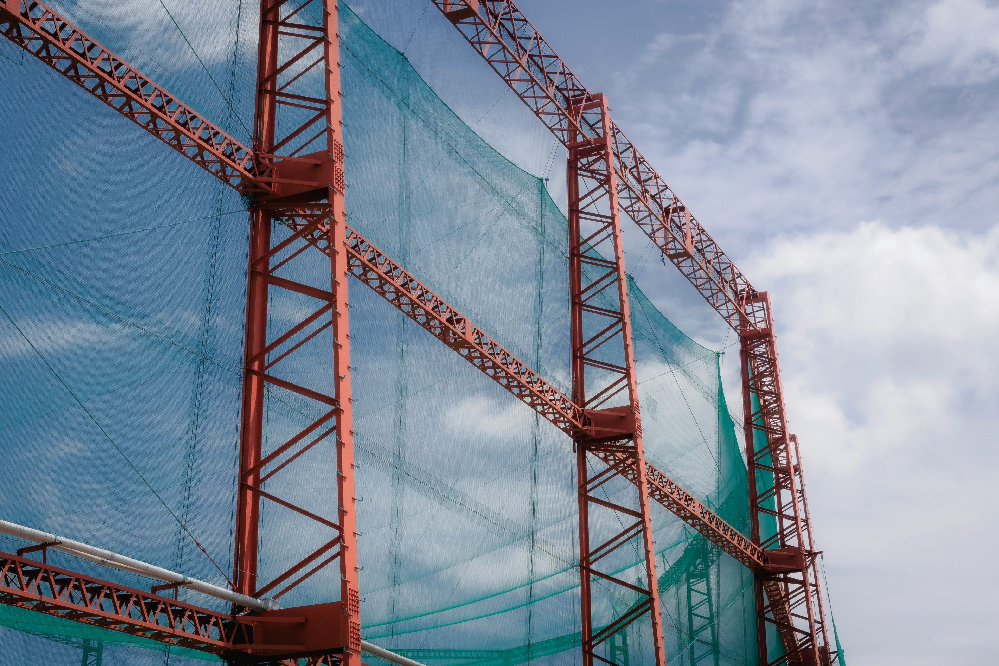 Structure de chantier recouverte de filets bleus et de cadres en acier rouge