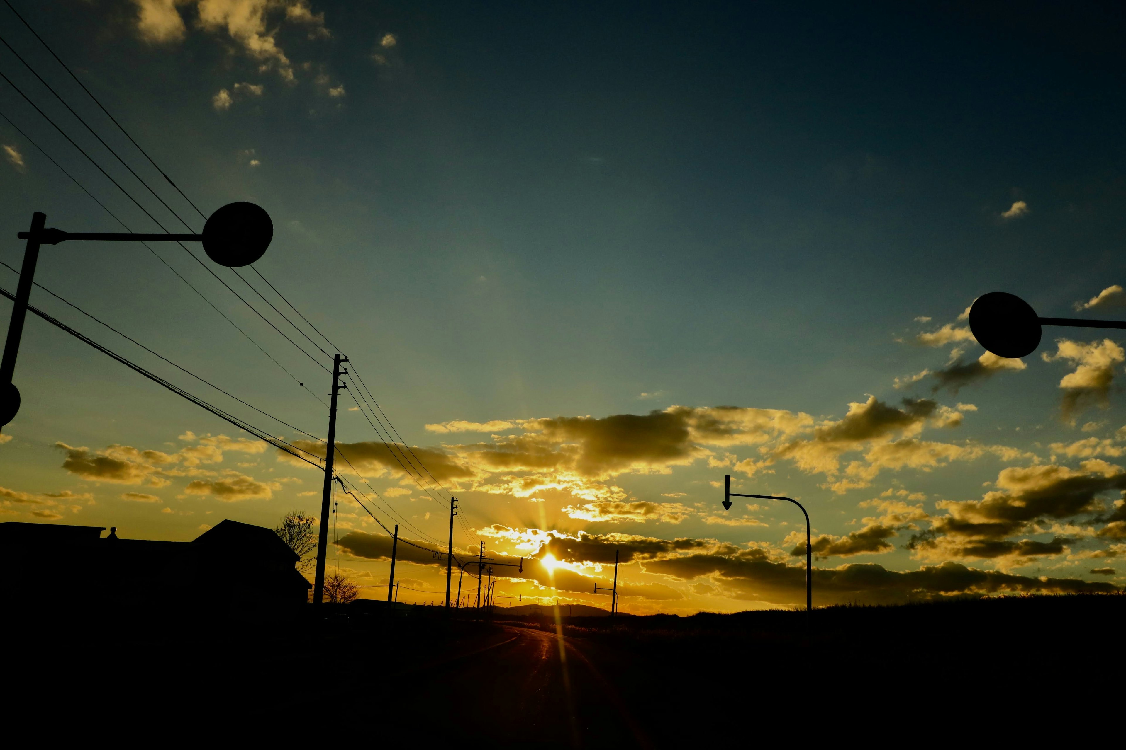 Paisaje de atardecer con nubes dispersas y estructuras en silueta