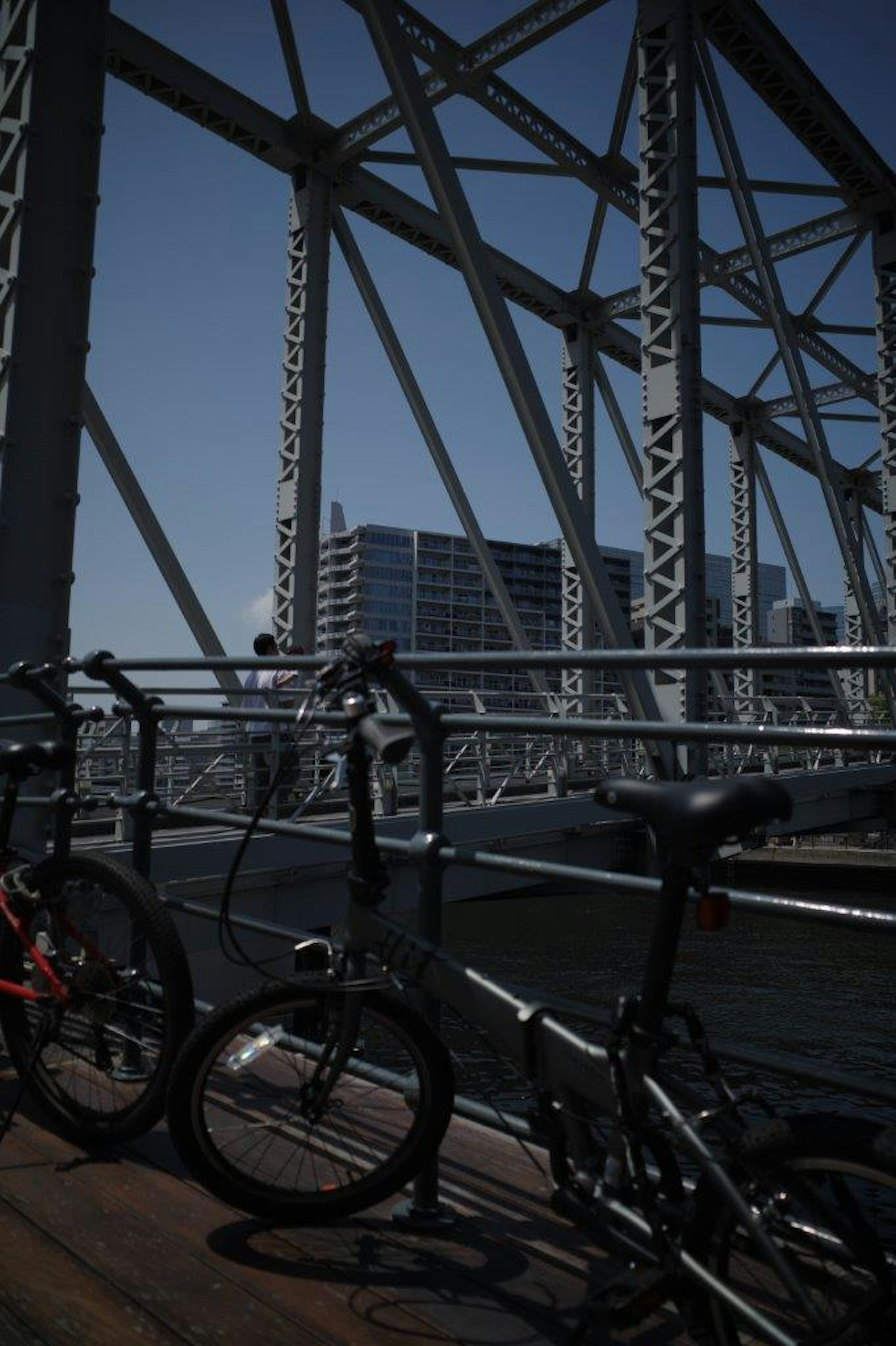 Bicicletas estacionadas en un puente con elementos estructurales y paisaje urbano al fondo