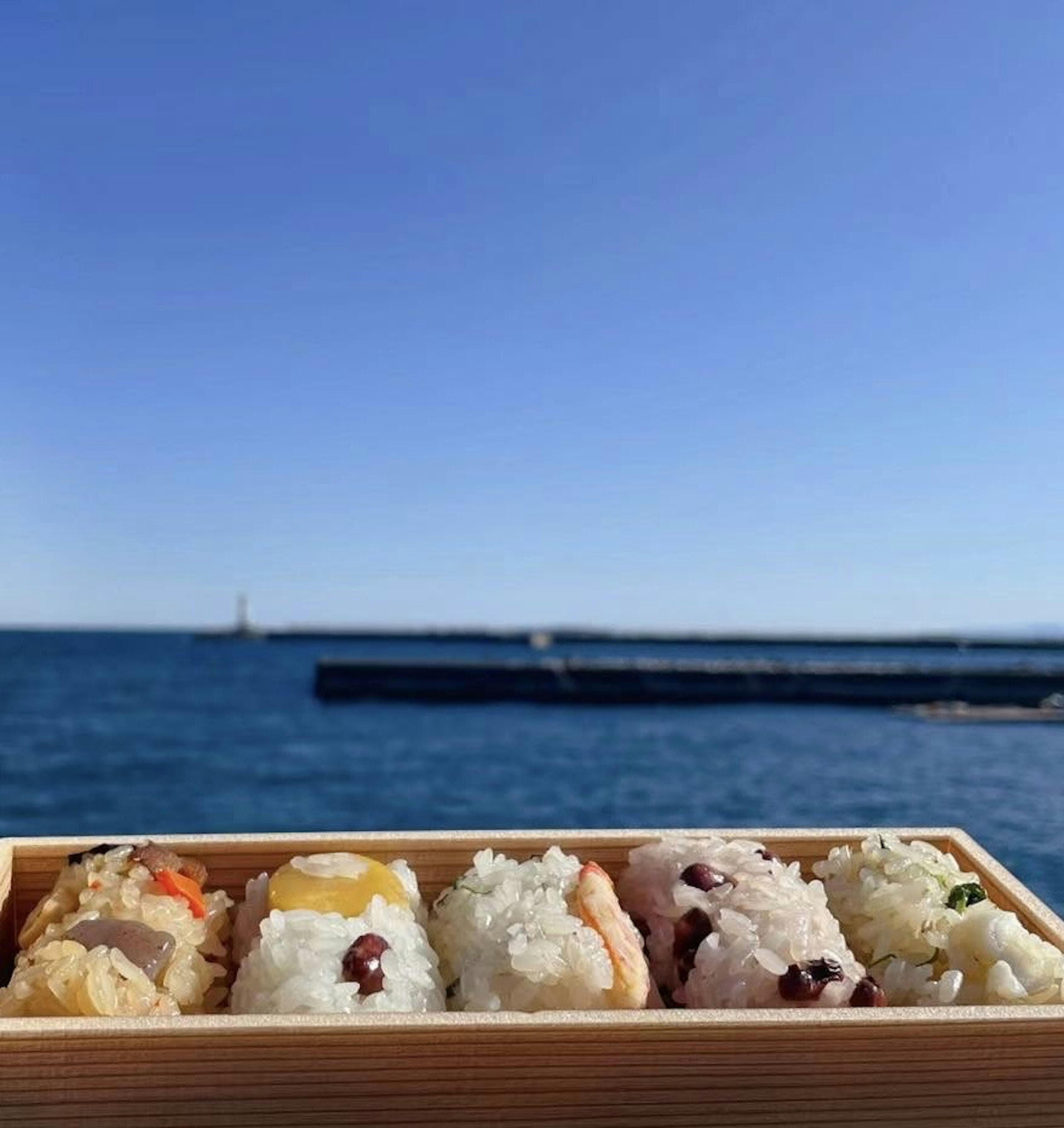 Un vassoio di sushi in una scatola di legno con vista sull'oceano