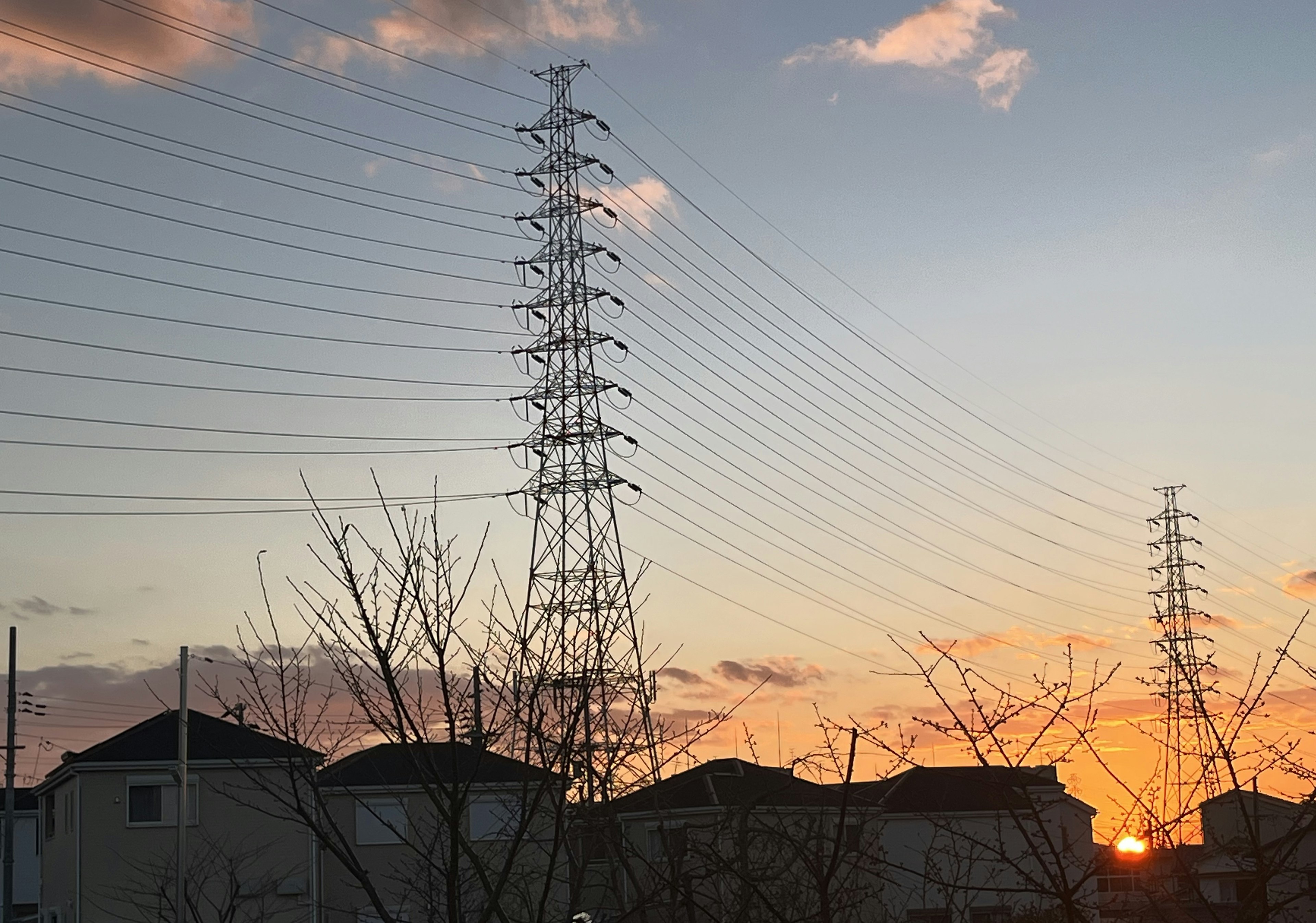 夕焼けの中に立つ電柱と住宅のシルエット