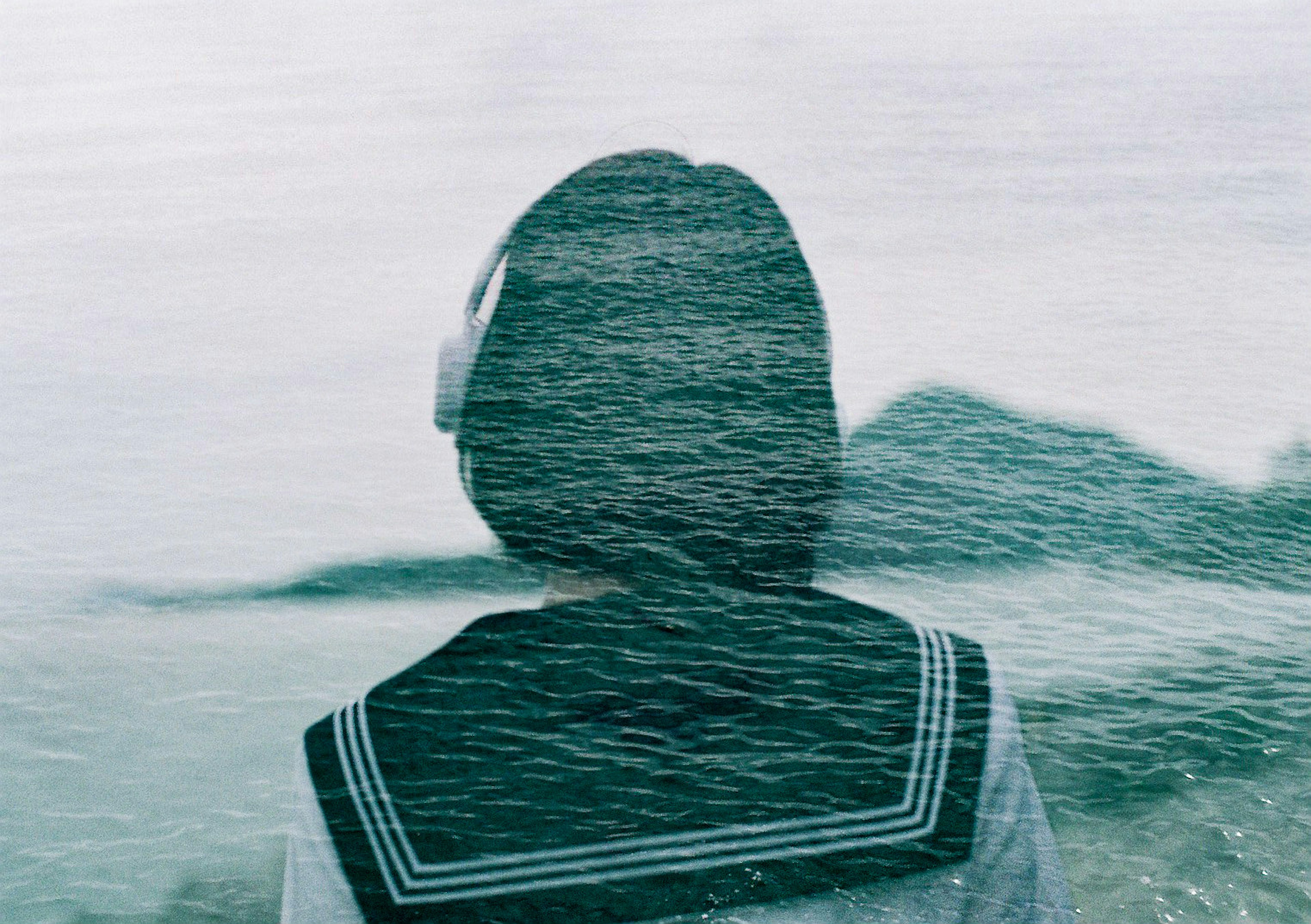 Back view of a girl in a sailor uniform facing the sea