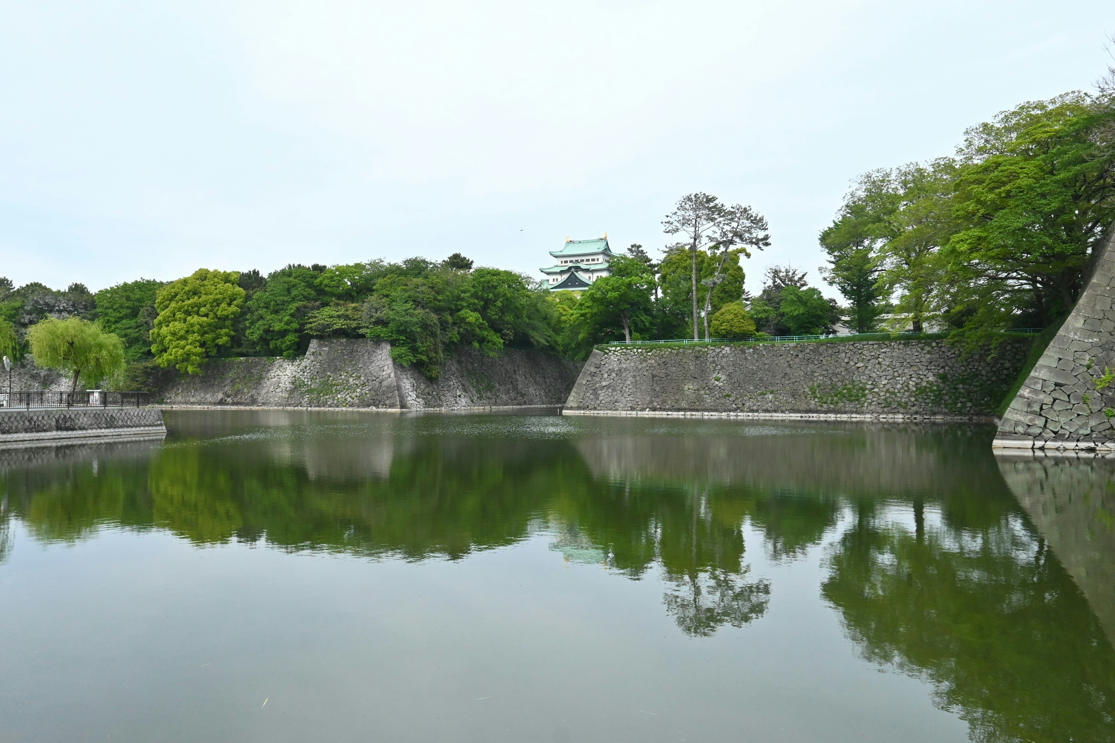 Tranquil water reflecting lush green castle walls and trees