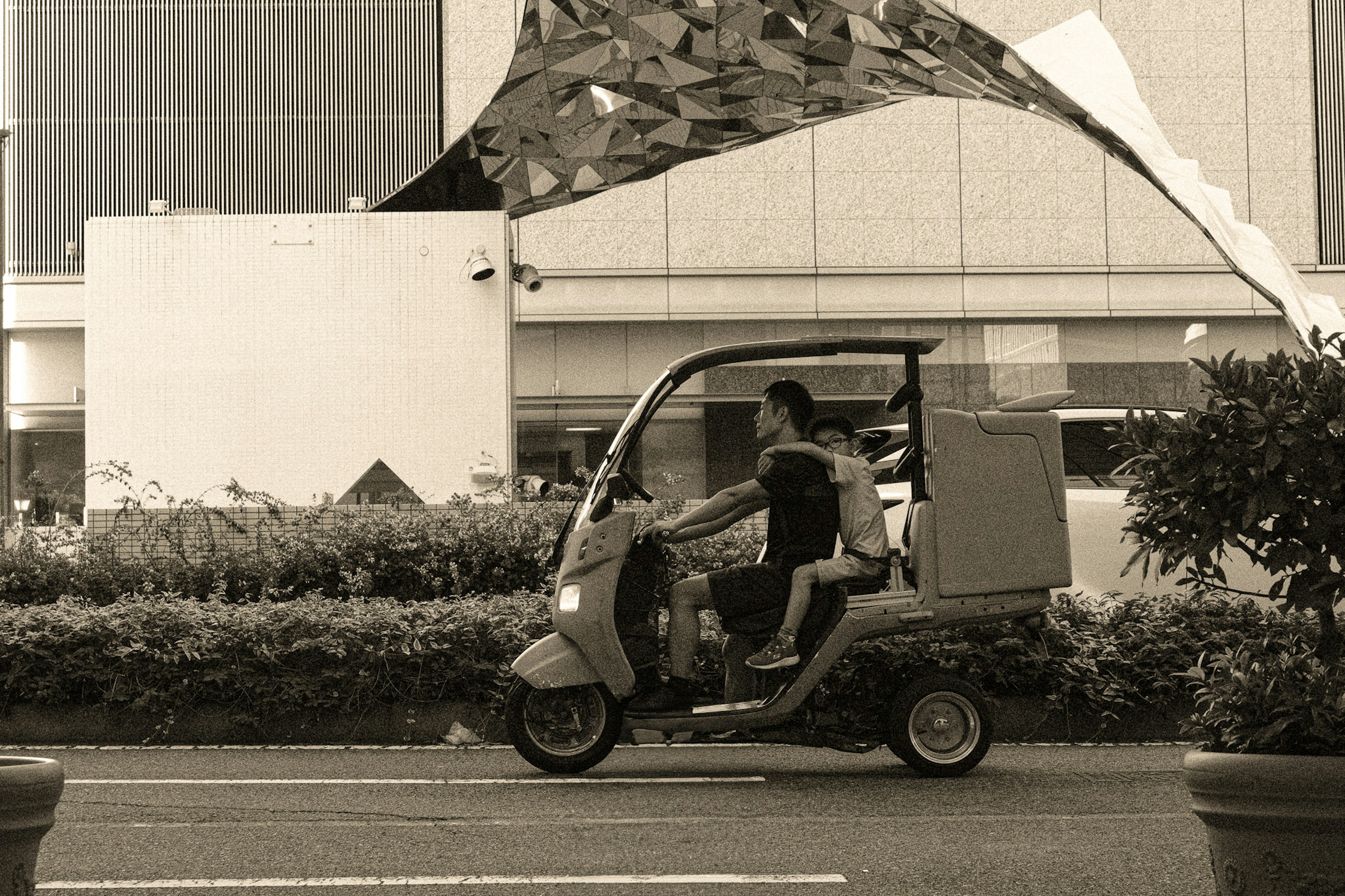 トライクに乗る二人の男性が都市の通りを走る様子