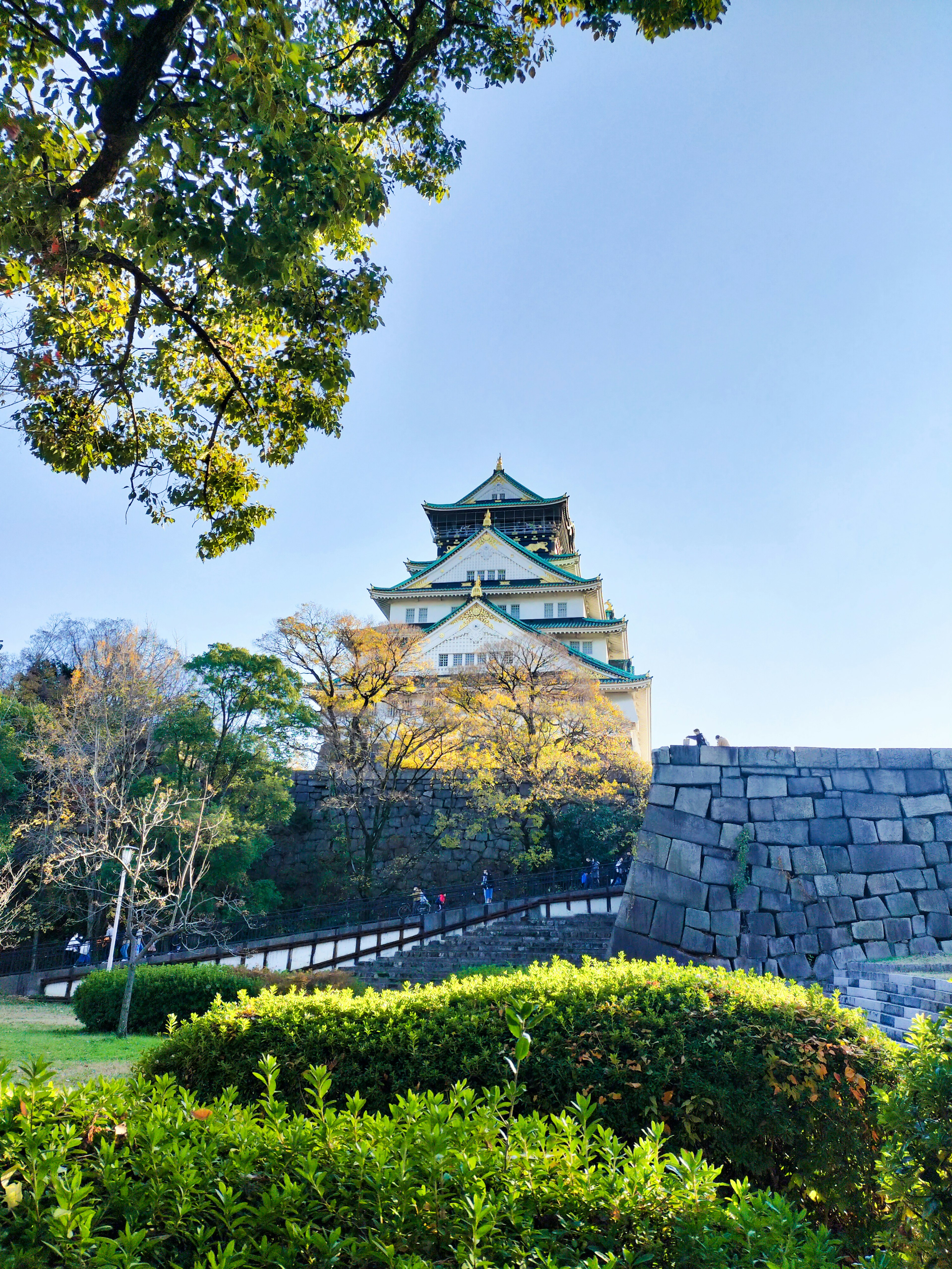 Osaka Castle with green trees and blue sky in the background