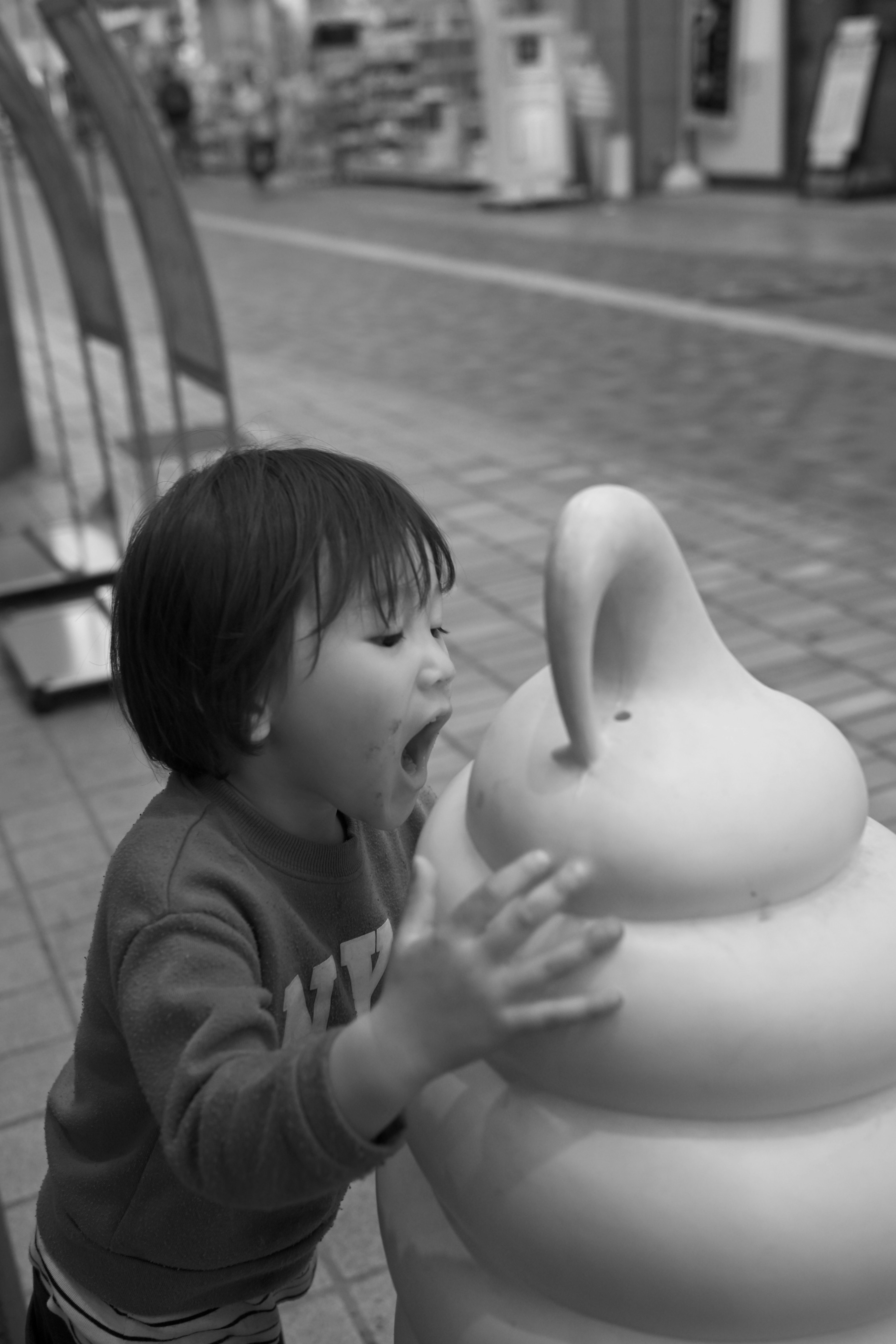 Bambino che interagisce con una scultura di gelato morbido in bianco e nero