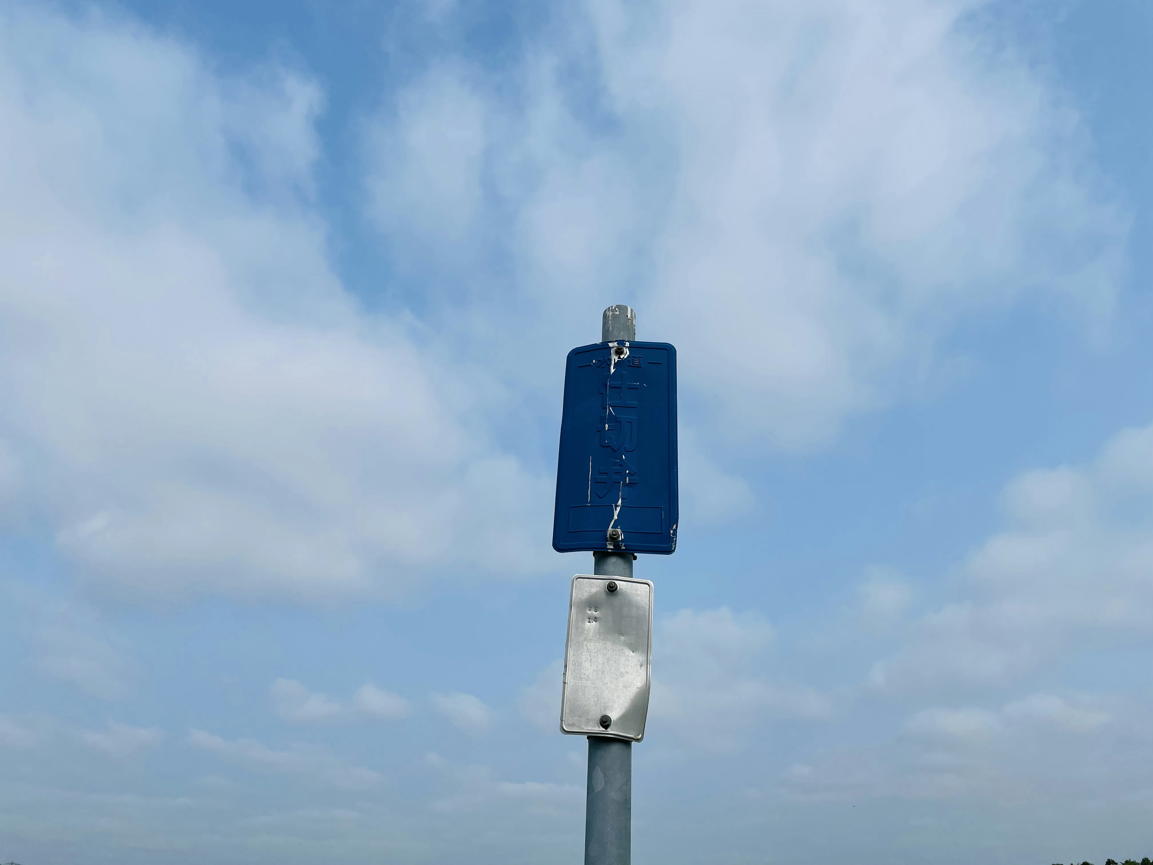 Un cartello blu si erge sotto un cielo blu