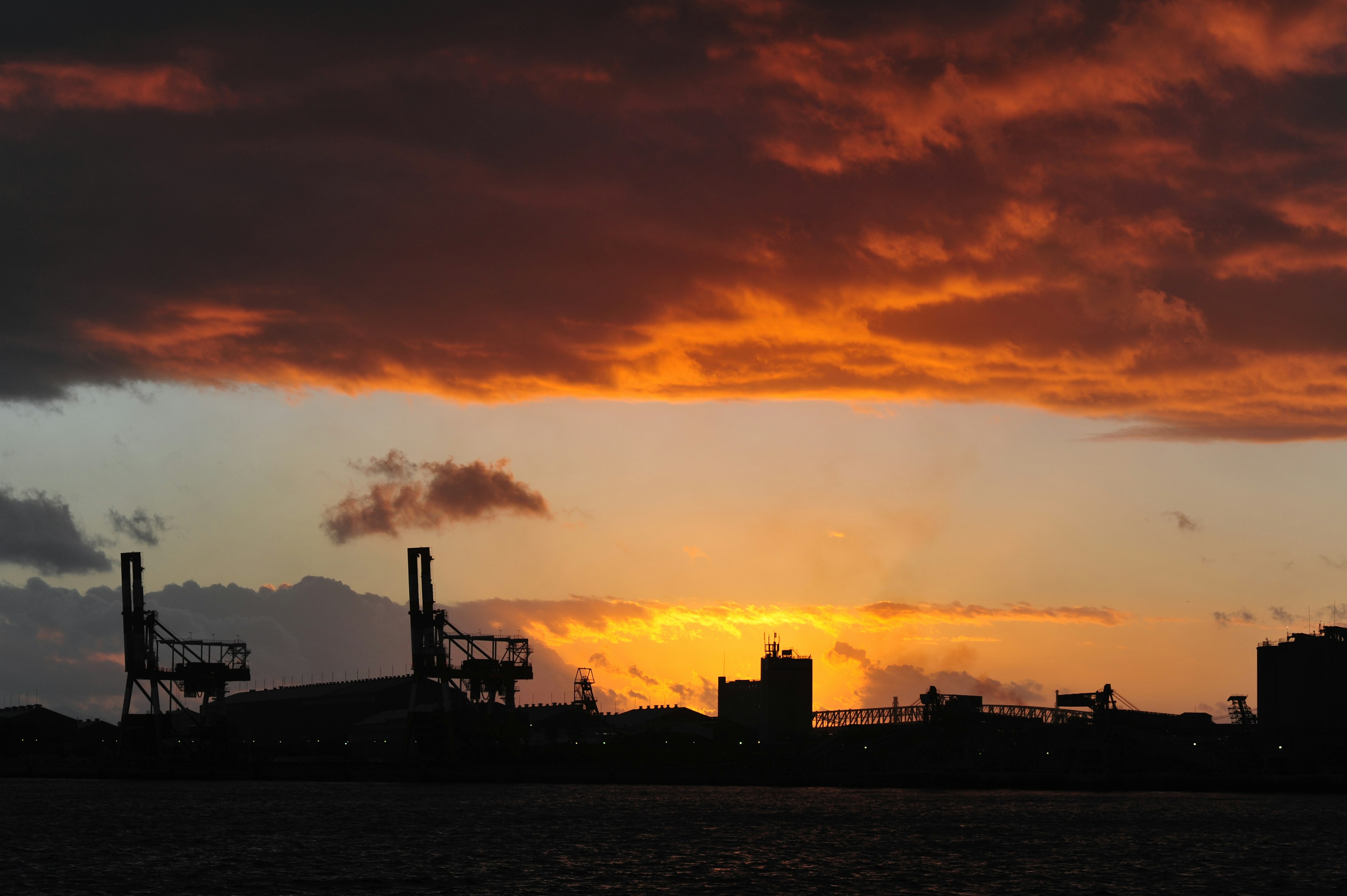 Silhouette of a port with cranes against a vibrant sunset