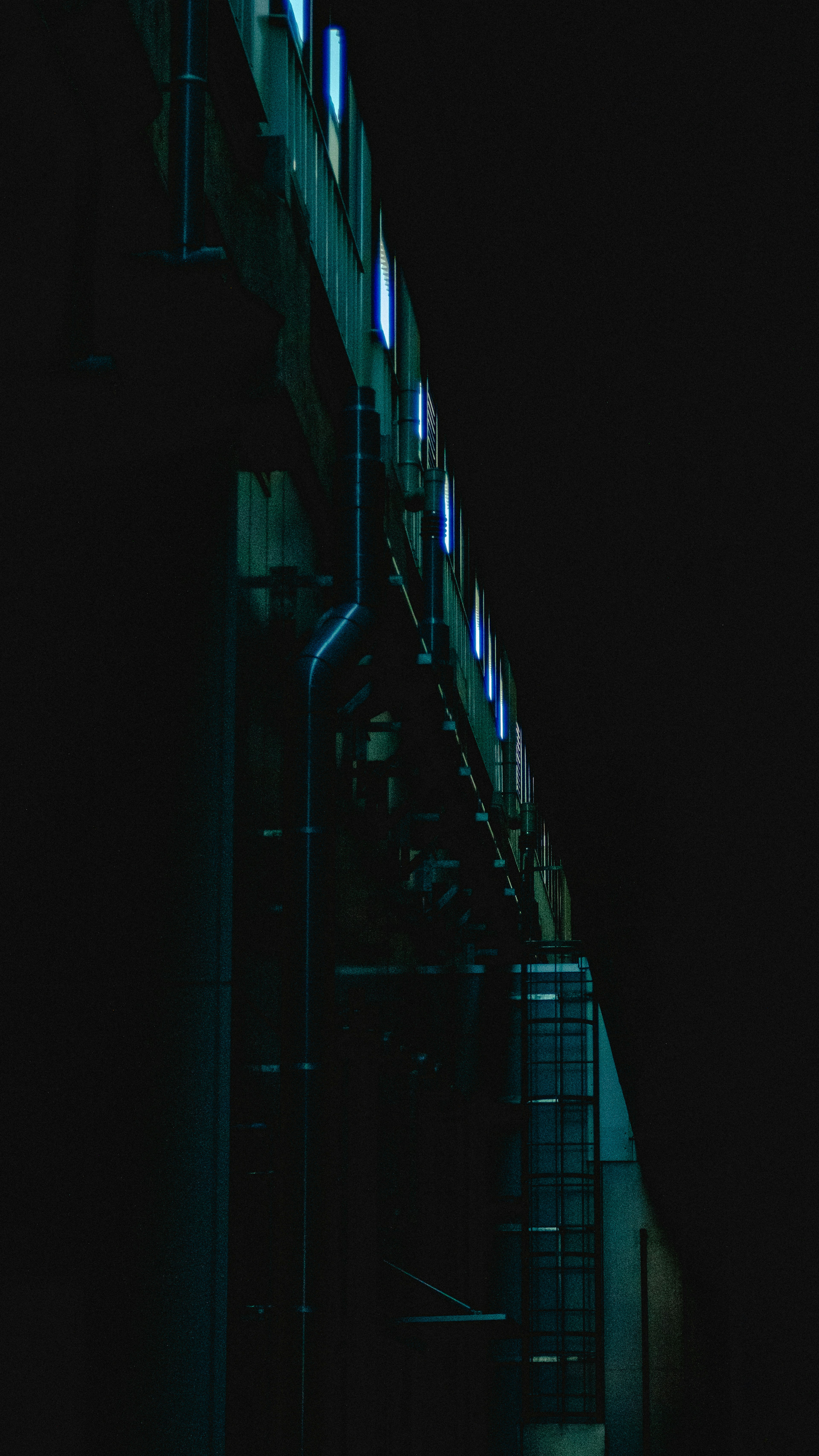 Part of a structure illuminated in teal against a dark background