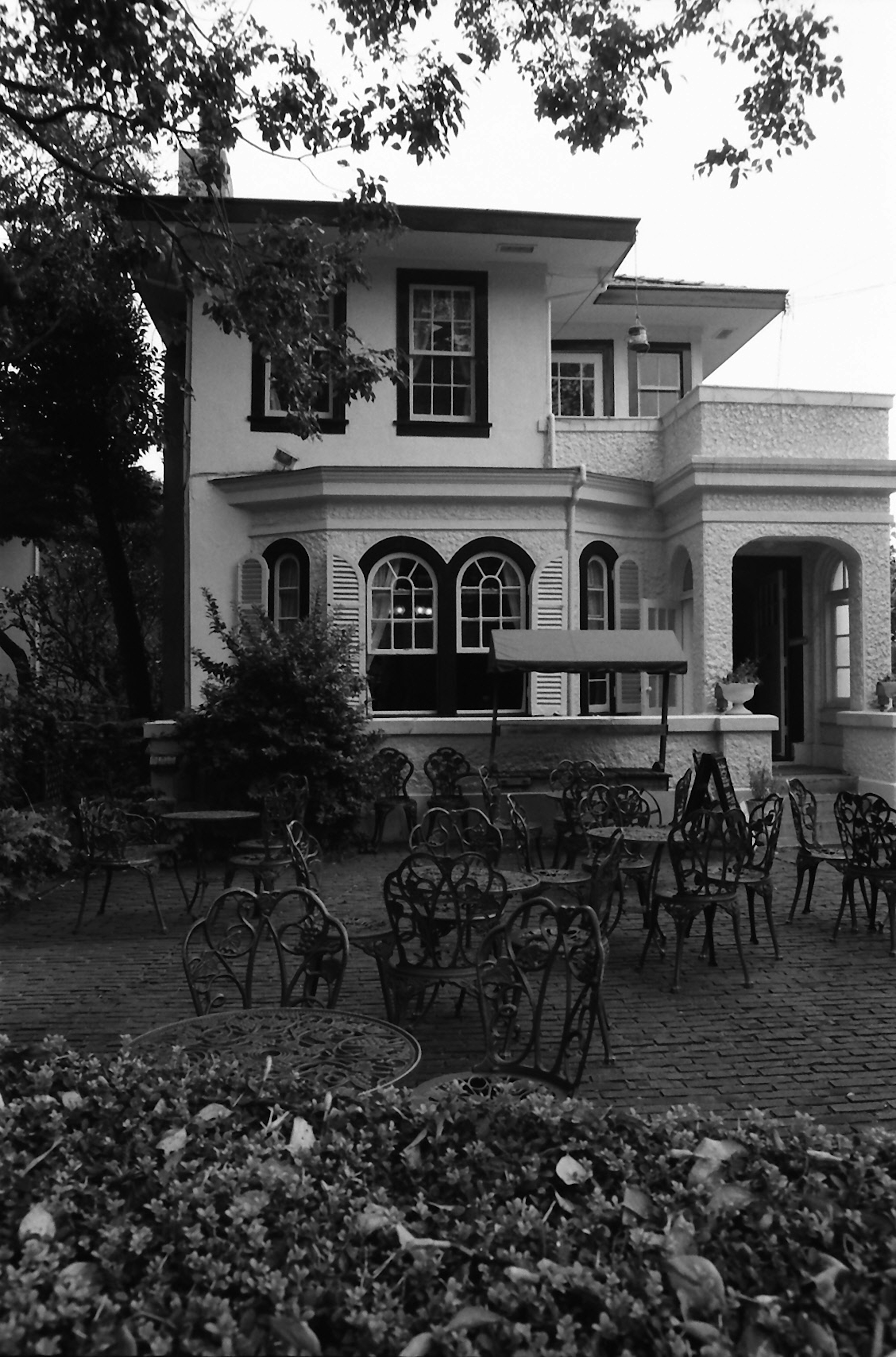 Black and white image of a beautiful house with garden seating